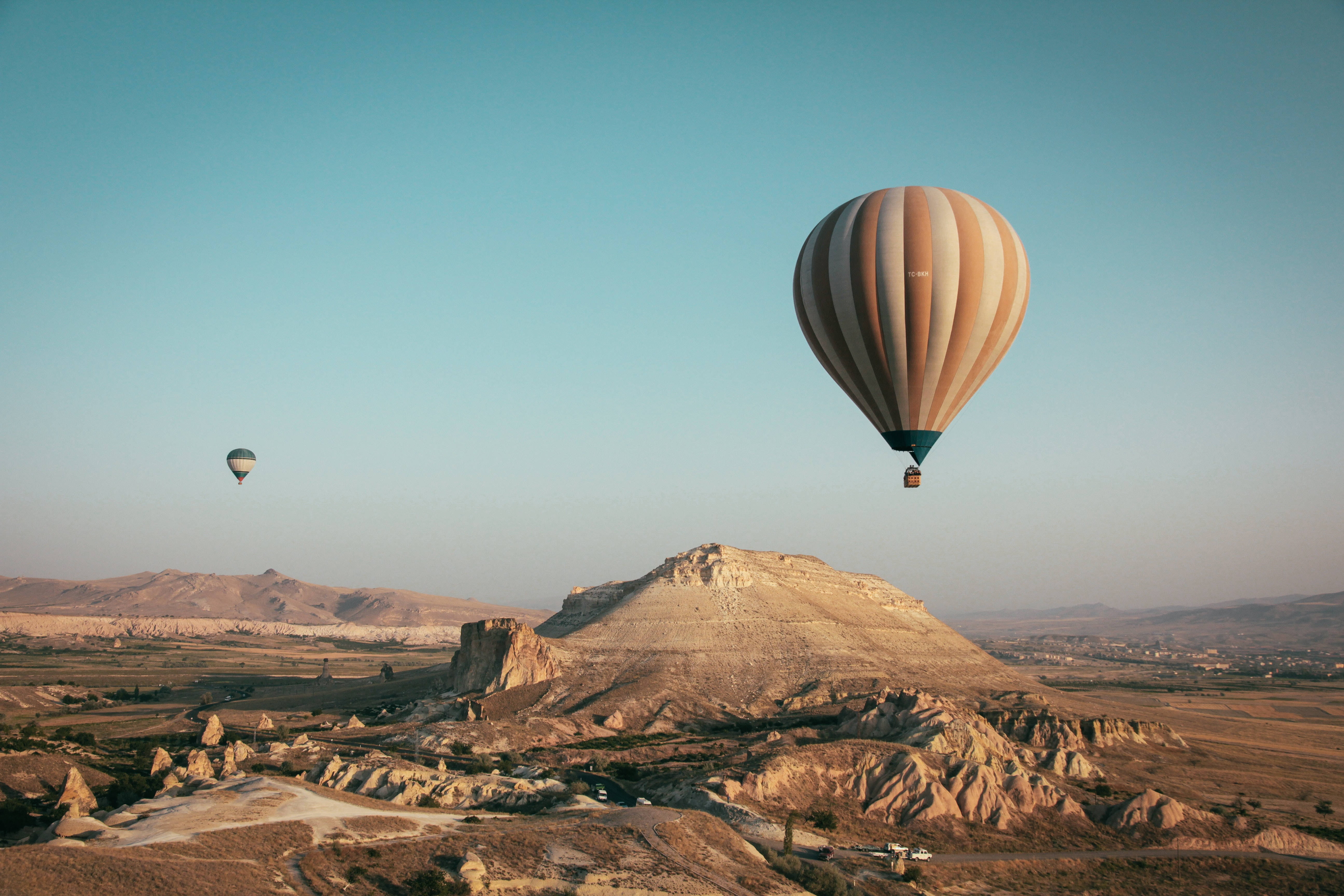 hot air balloon, rugged volcanic rock formations, clear blue sky, 5K Desktop Wallpaper