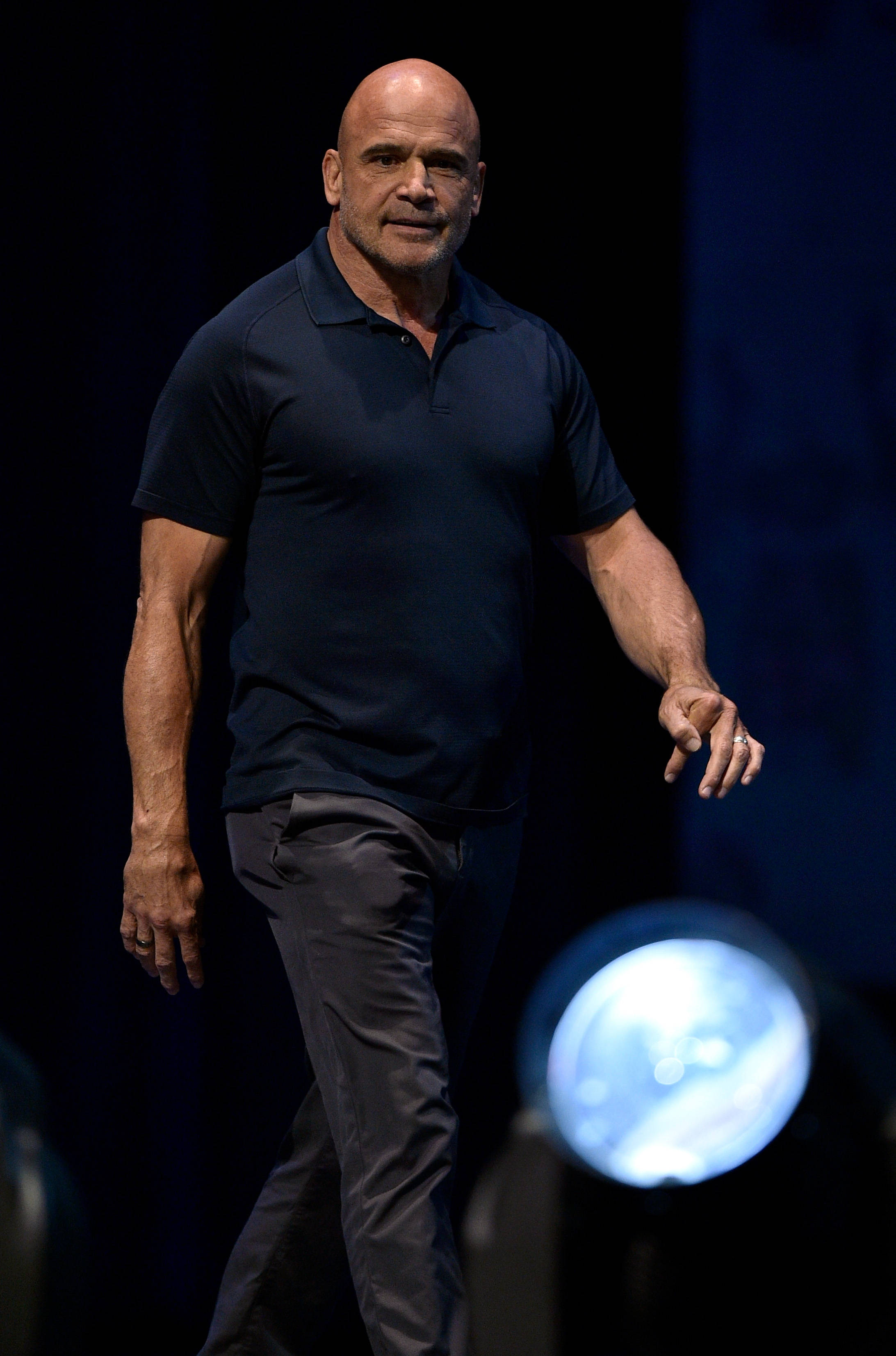 Bas Rutten, dark polo shirt, dimly lit stage, 2K Phone Wallpaper