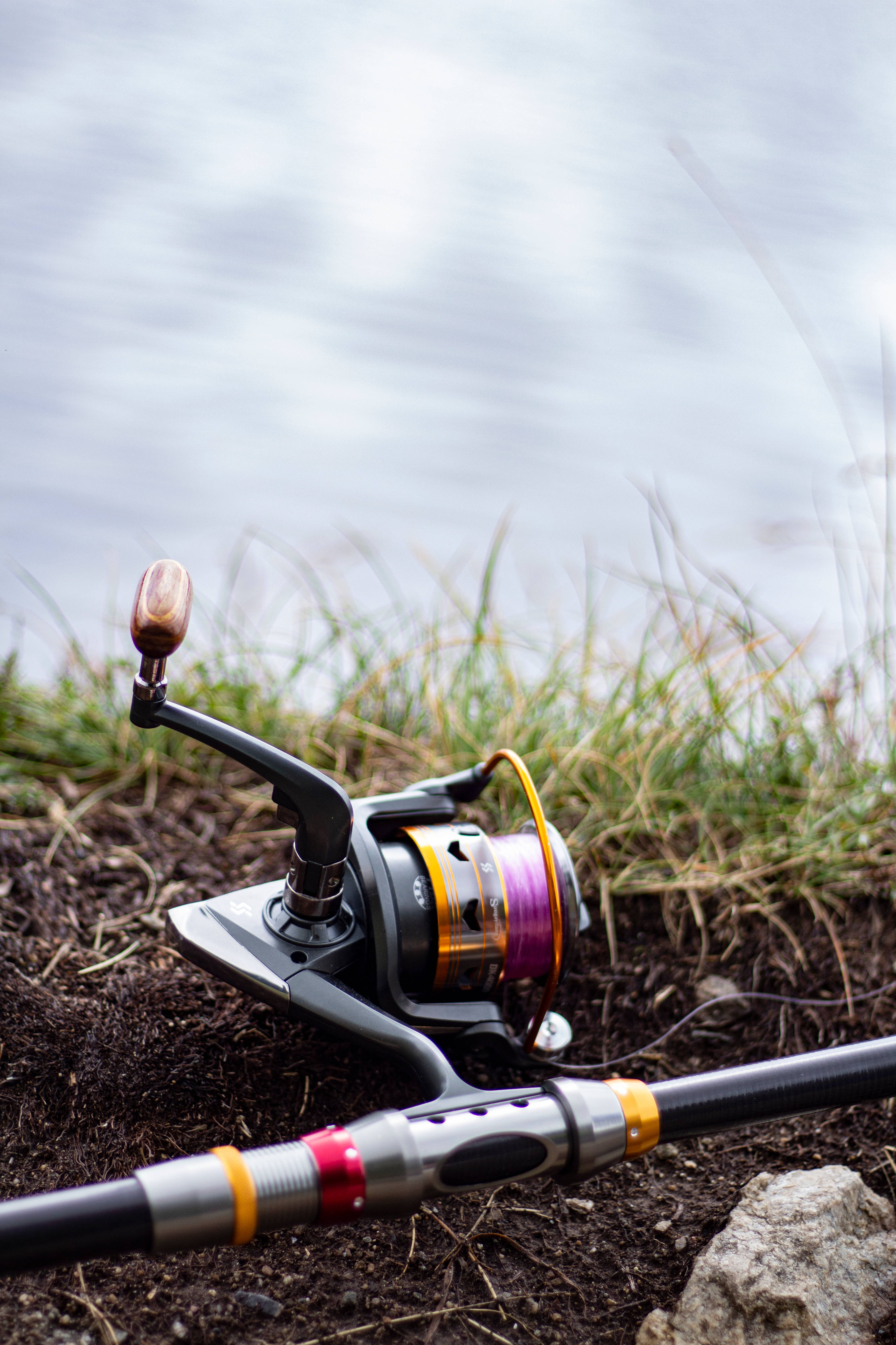Bass Fishing Rod, purple spool, muddy ground, 5K Phone Wallpaper