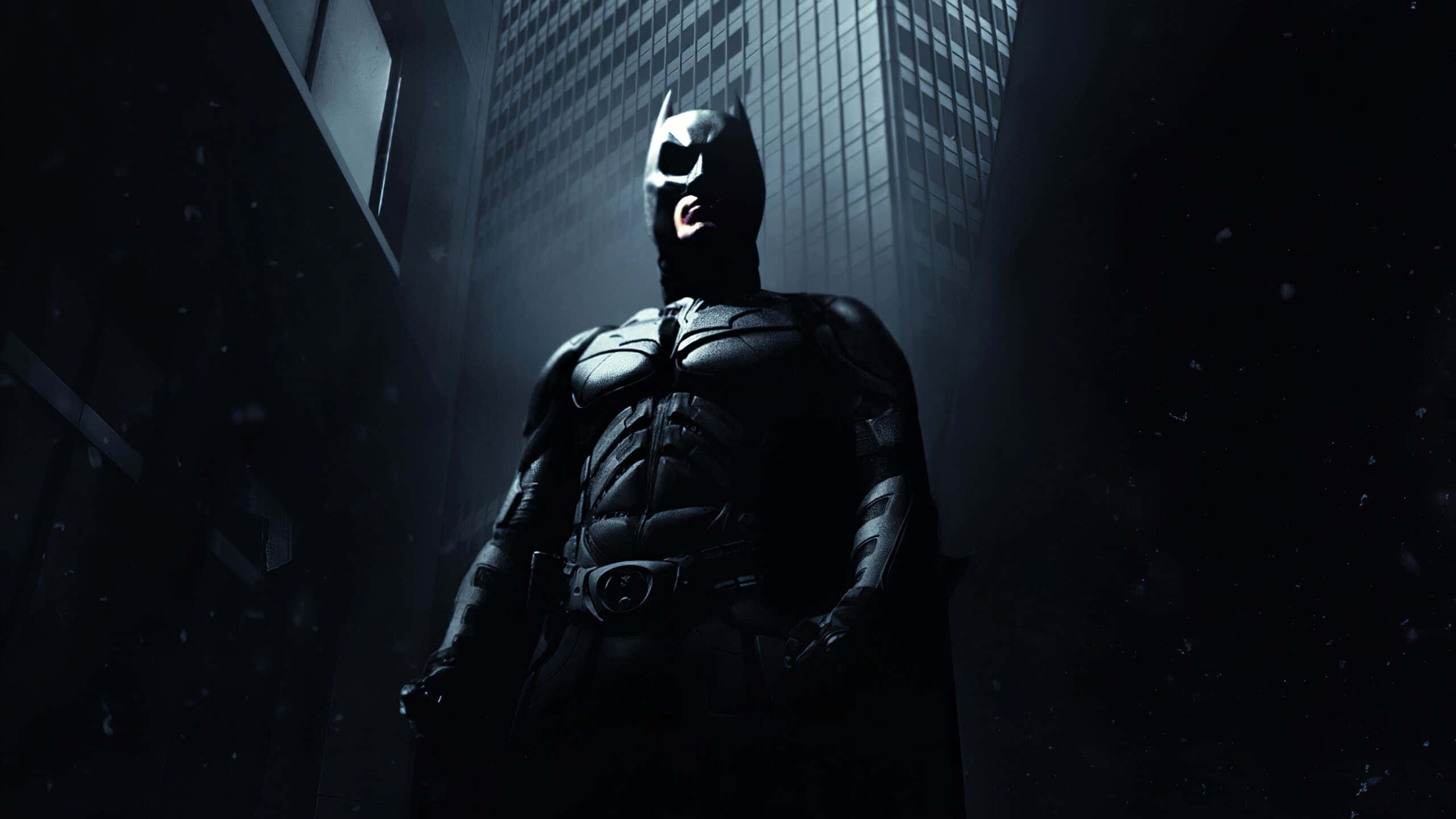 Batman, dark rain-soaked alley, towering skyscrapers, 2K Desktop Wallpaper