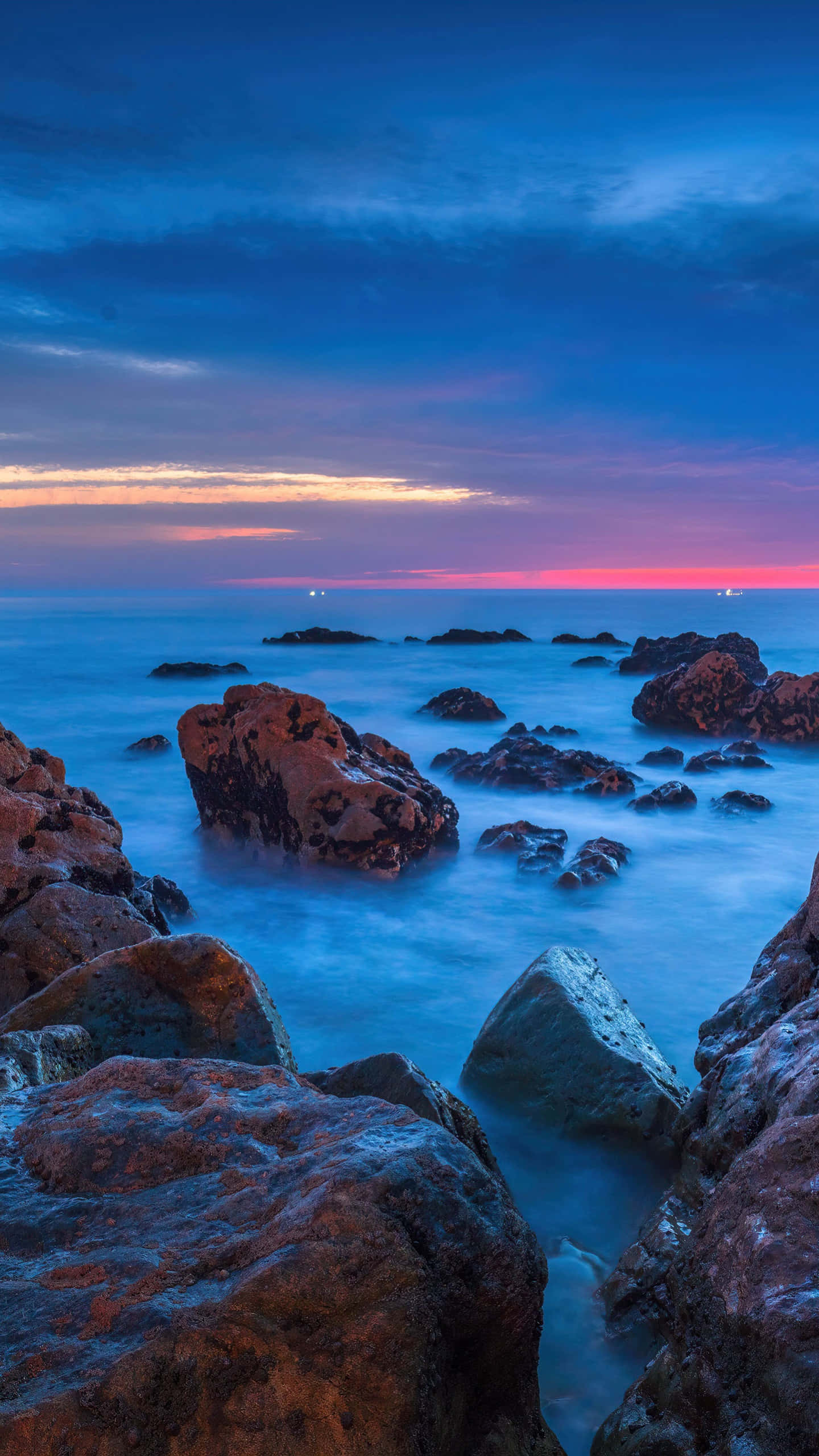 twilight seascape, smooth blue water, rugged rocks, 2K Phone Wallpaper