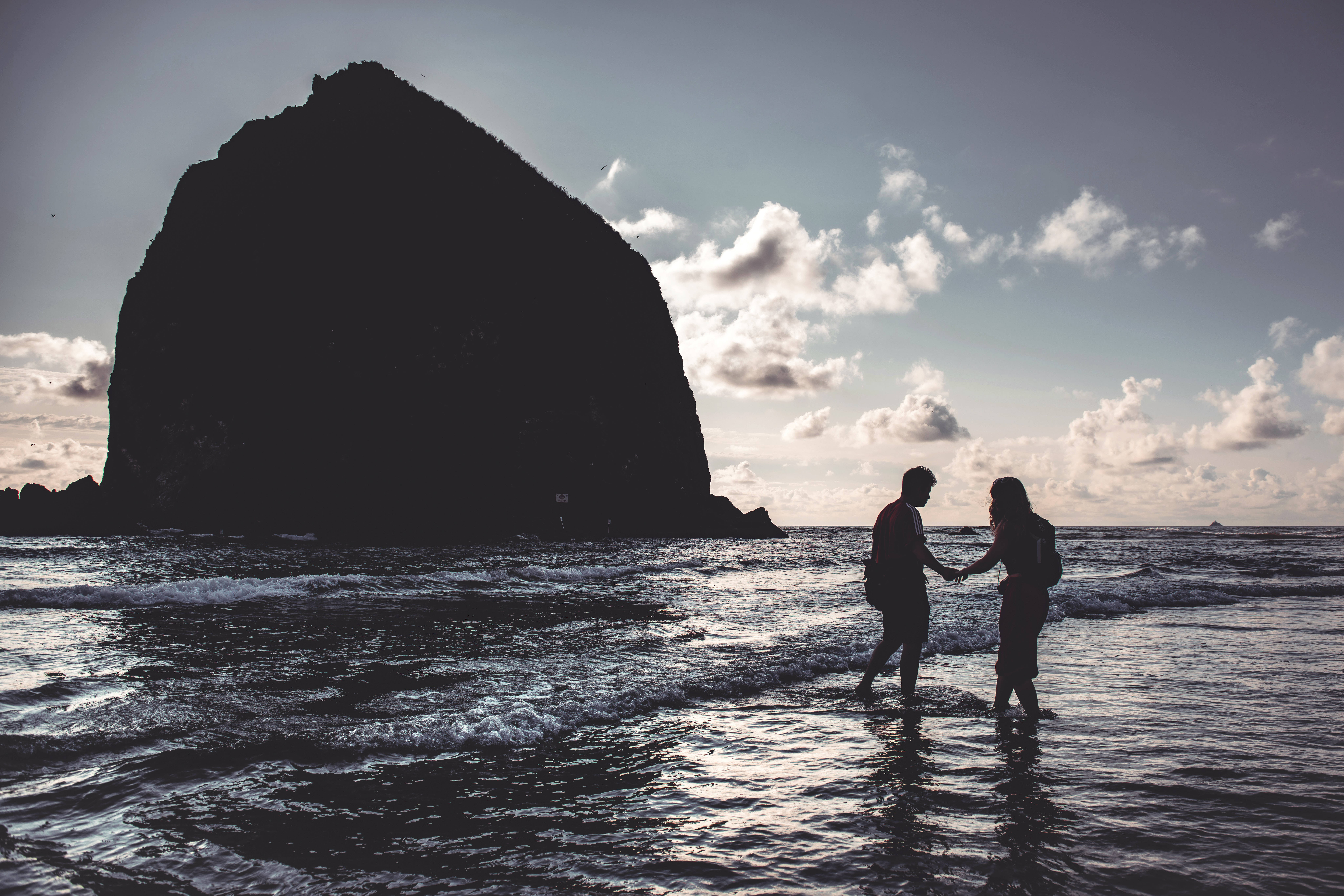 Lovers In The Shore, shallow ocean waves, massive dark rock formation, 8K Desktop Wallpaper