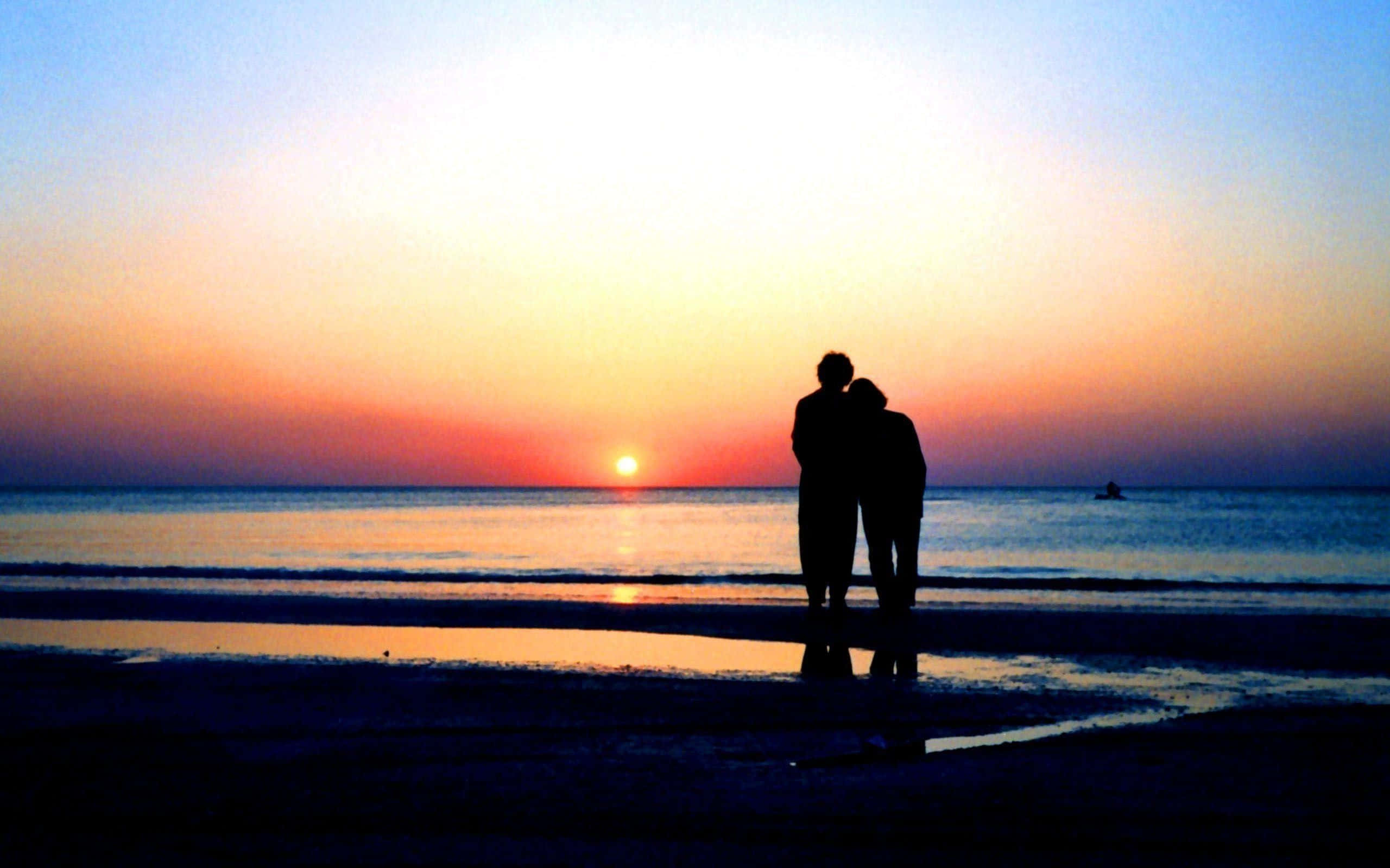 Romantic Sunset Beach Stroll, silhouetted couple, fiery orange and soft blue hues, 2K Desktop Wallpaper