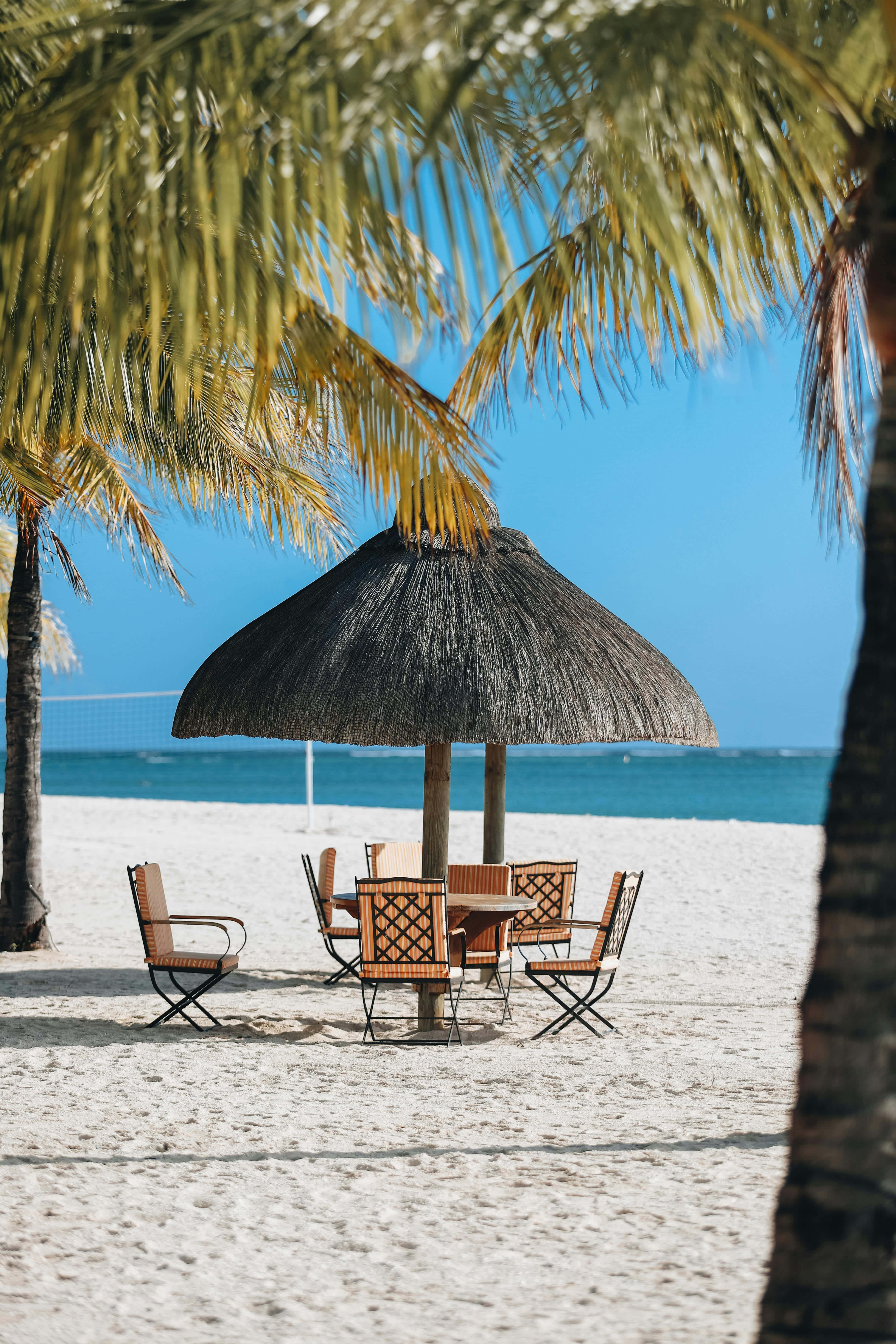 thatched umbrella, wooden table and chairs, pristine white sandy beach, 5K Phone Wallpaper