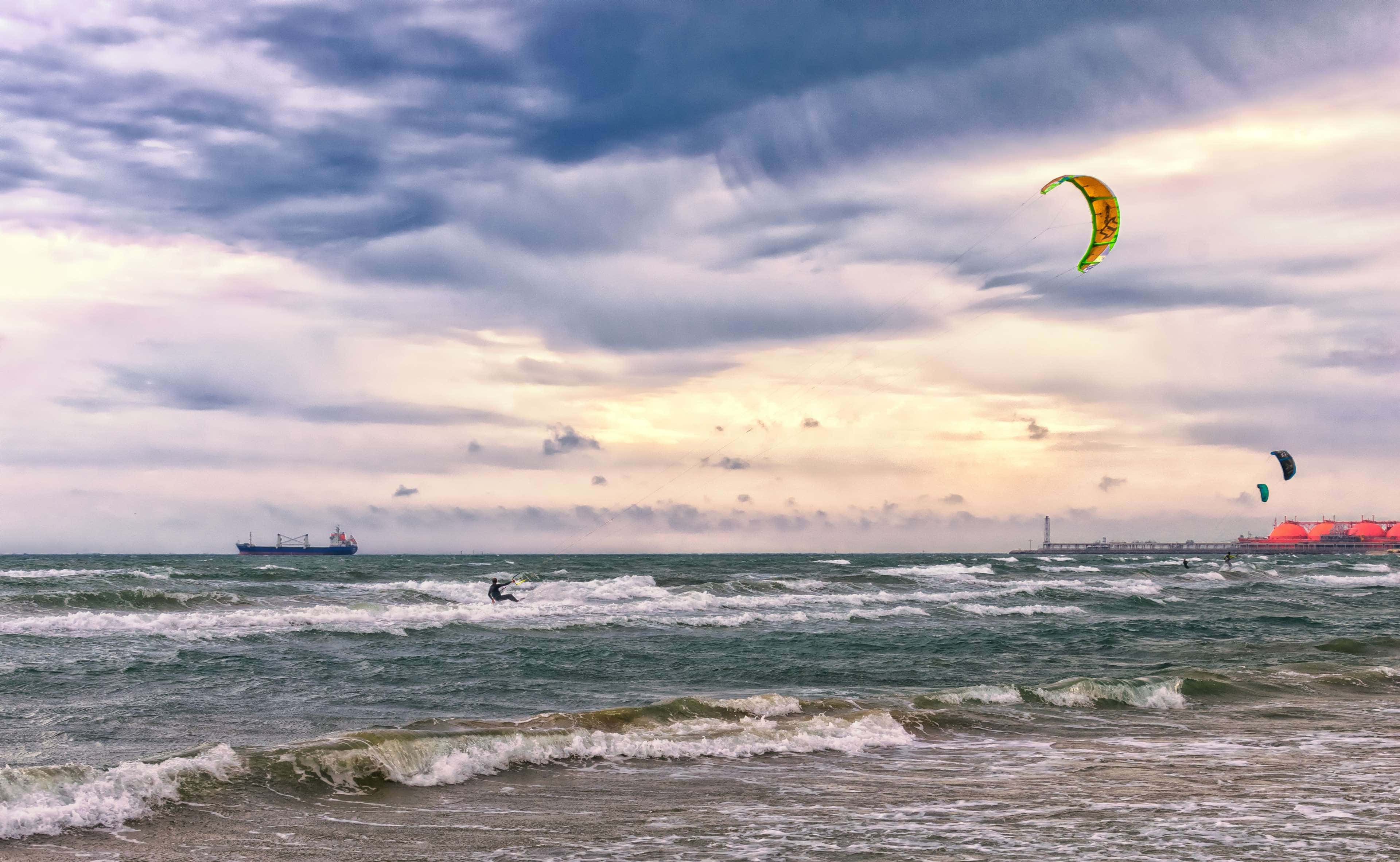 kite surfers, choppy ocean waves, dramatic cloudy sky, 4K Desktop Wallpaper