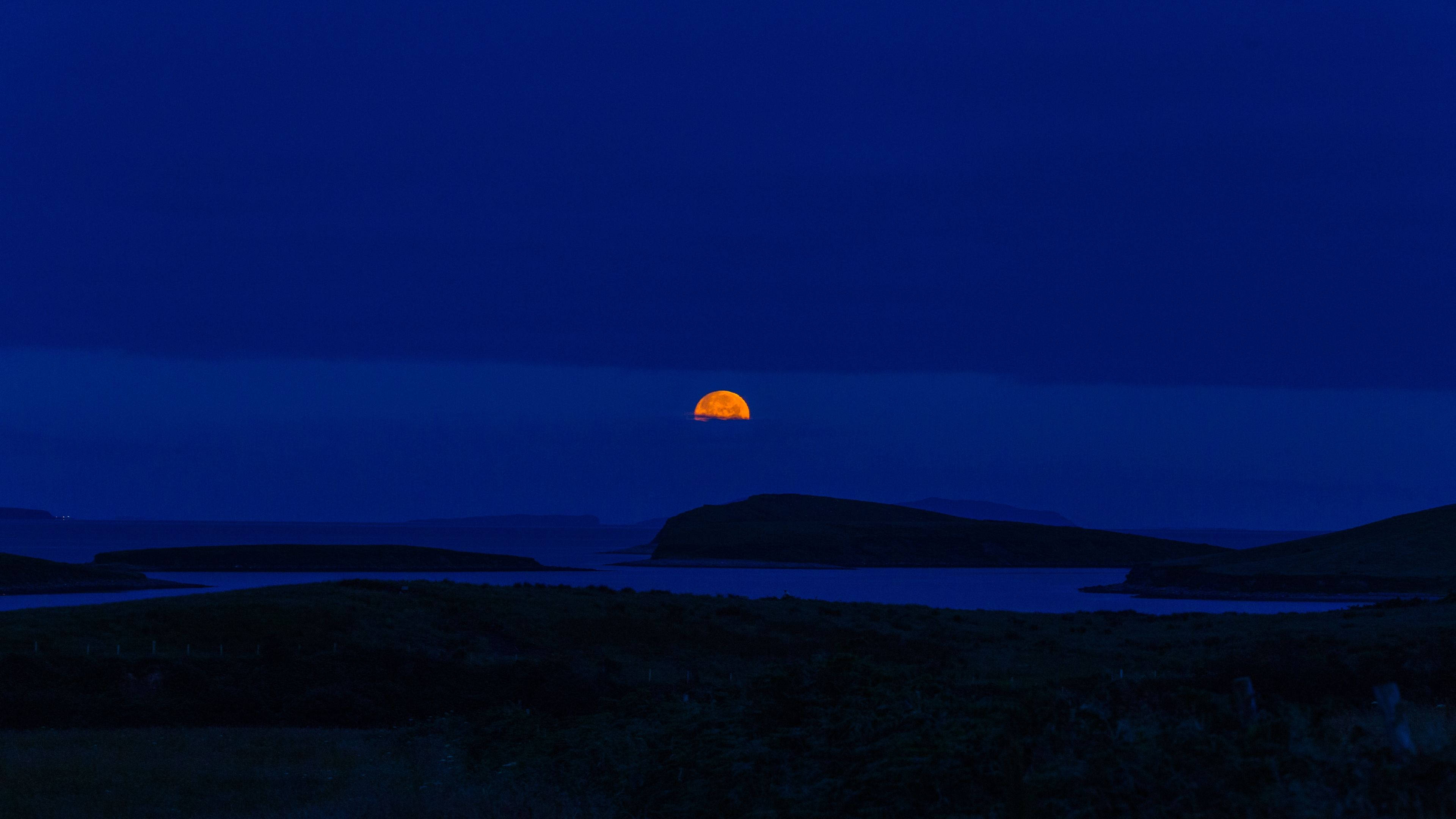 glowing orange moon, dark silhouetted hills, water, 4K Desktop Wallpaper