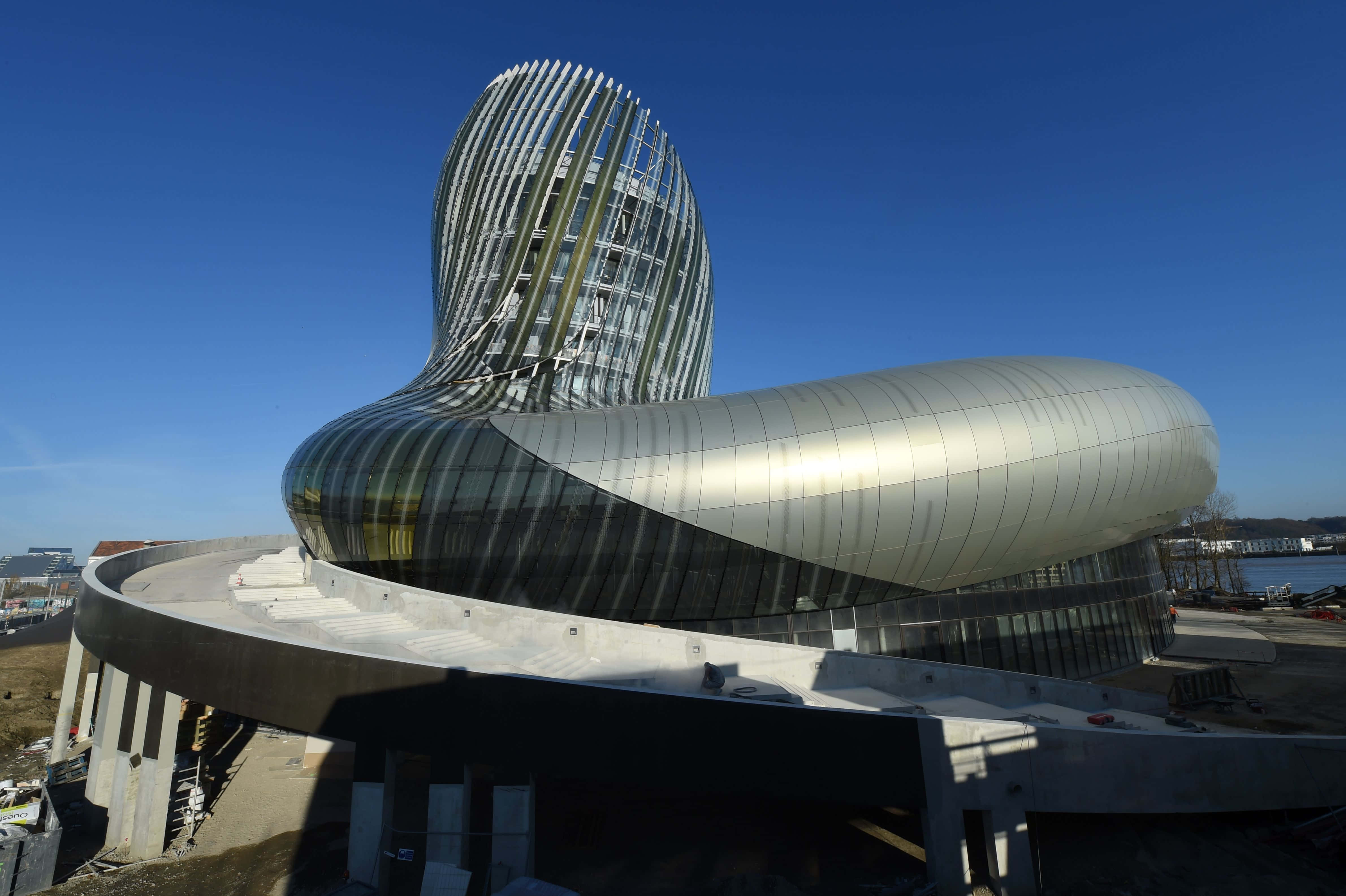 futuristic silver and glass building, twisting spiral roof, clear blue sky, 4K Desktop Wallpaper
