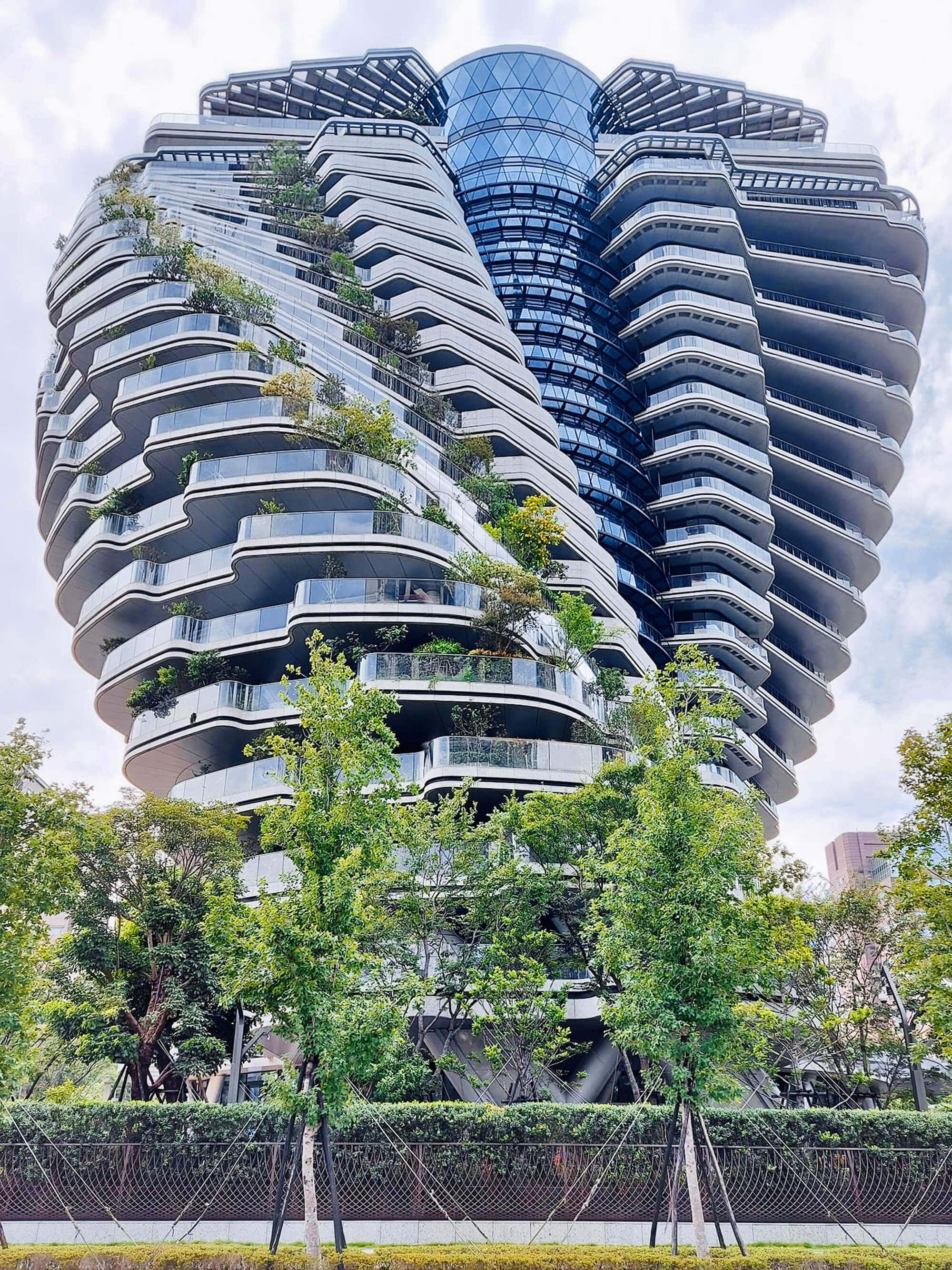 futuristic glass skyscraper, curved balconies, lush greenery, 2K Phone Wallpaper