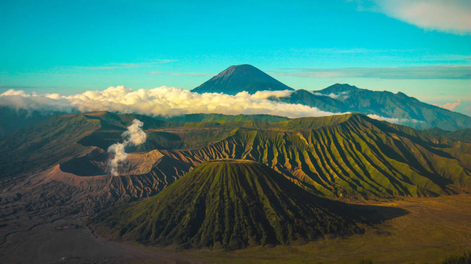 bright blue sky, lush green volcanic landscape, steam rising from a crater, SD Desktop Wallpaper