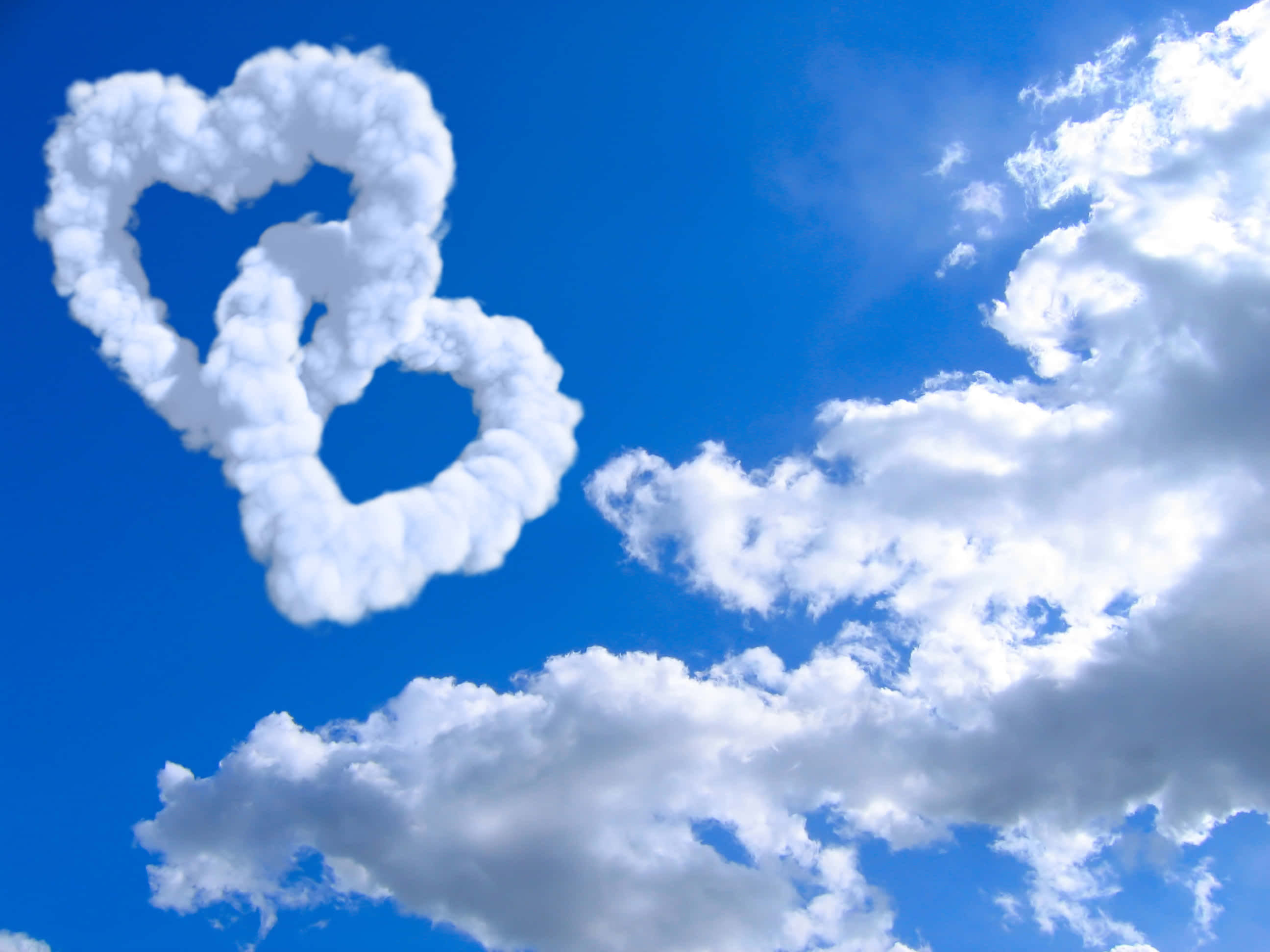 sunset sky, fluffy white heart-shaped clouds, vibrant blue sky, 2K Desktop Wallpaper