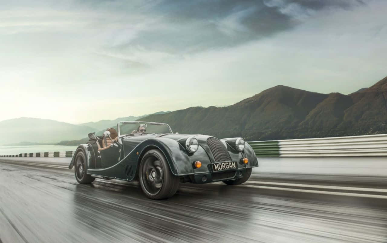 vintage green Morgan sports car, wet coastal road, mountains in the misty background, HD Desktop Wallpaper