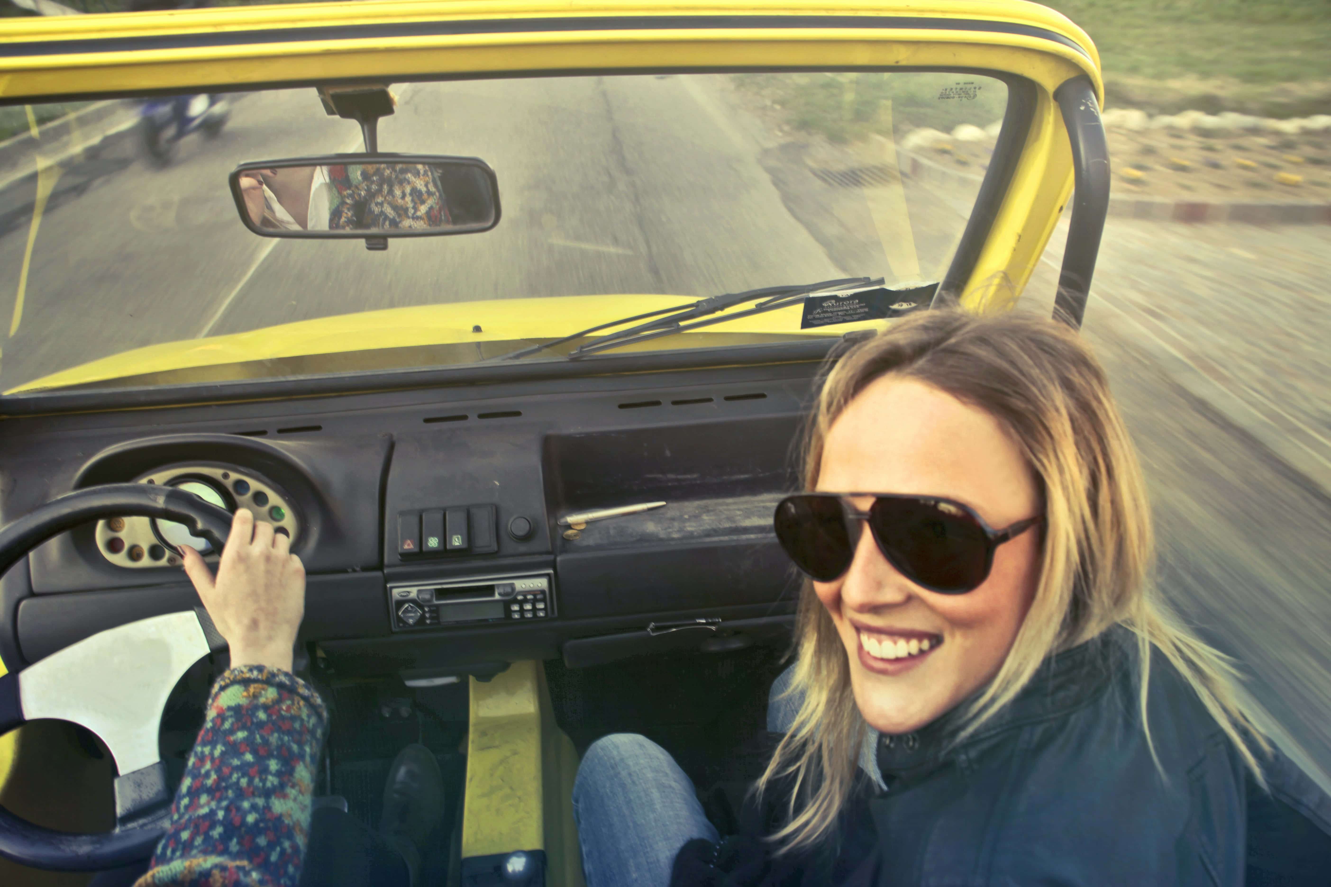 yellow open-top car, sunlit road, smiling woman in sunglasses, 5K Desktop Wallpaper