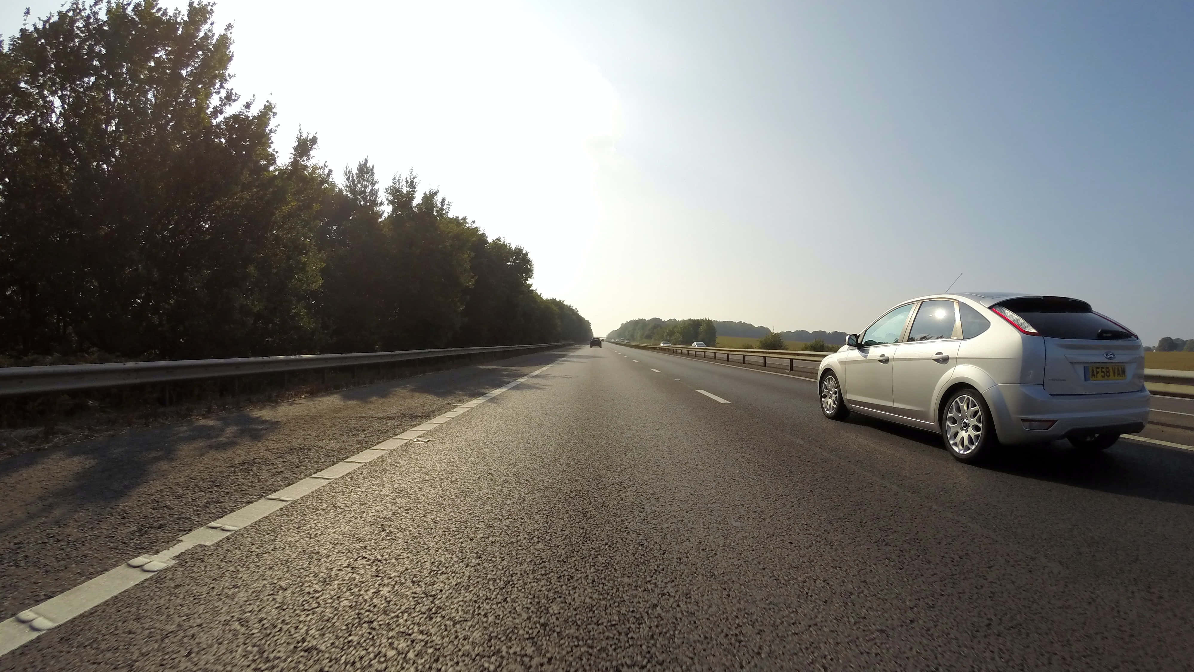 silver car, sunlit highway, dense trees, 4K Desktop Wallpaper