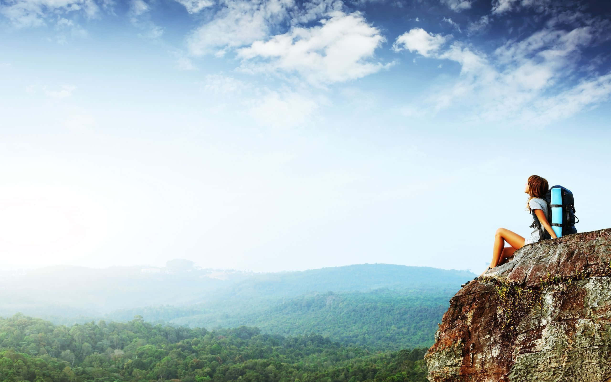 blue backpack, rugged cliff, vast green forest, 2K Desktop Wallpaper