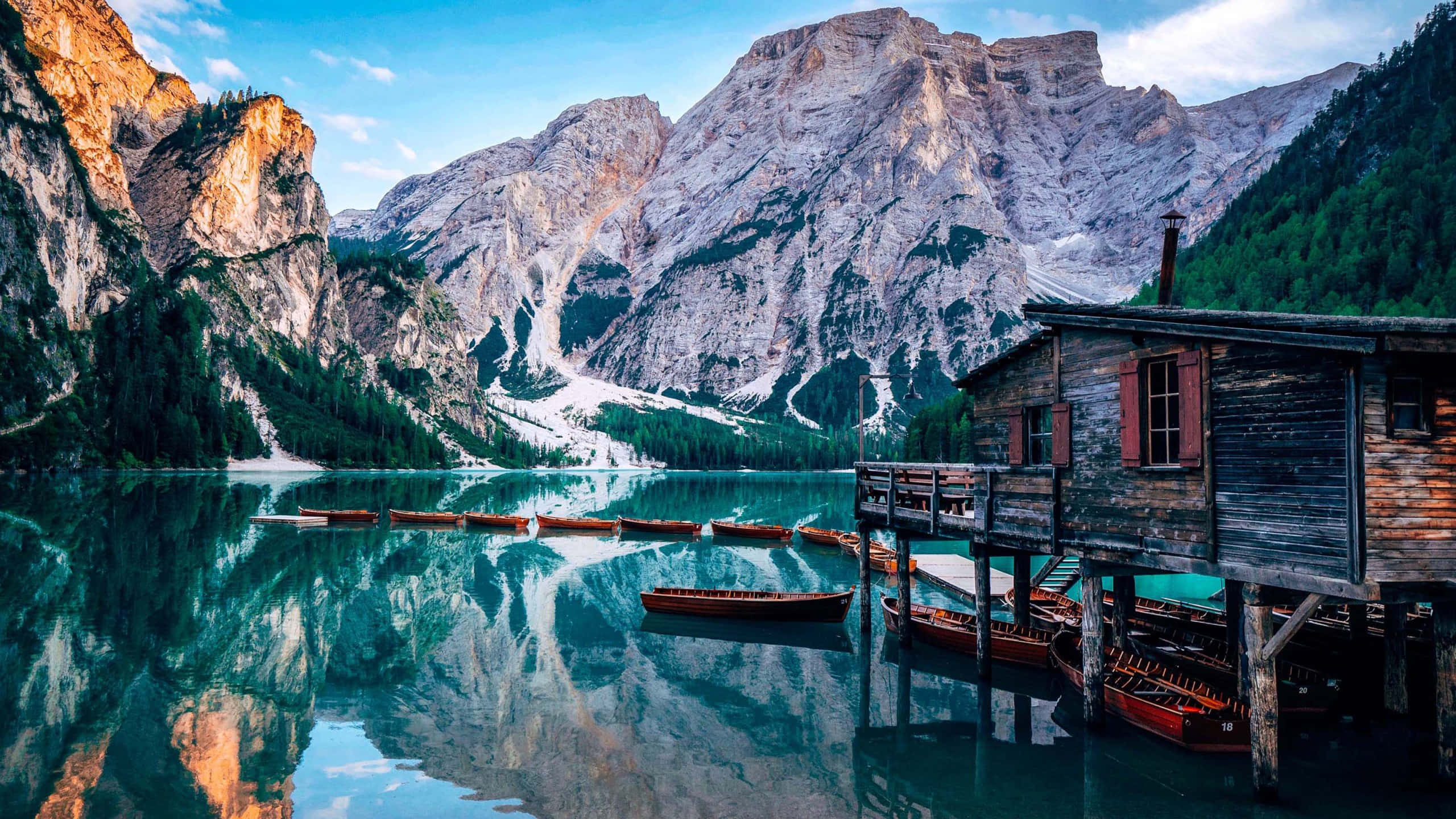 rustic wooden boathouse, glassy turquoise lake, towering rocky mountains, 2K Desktop Wallpaper