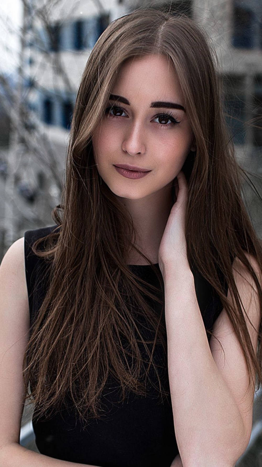 long brown hair, gazing softly at the camera, blurred urban backdrop, HD Phone Wallpaper