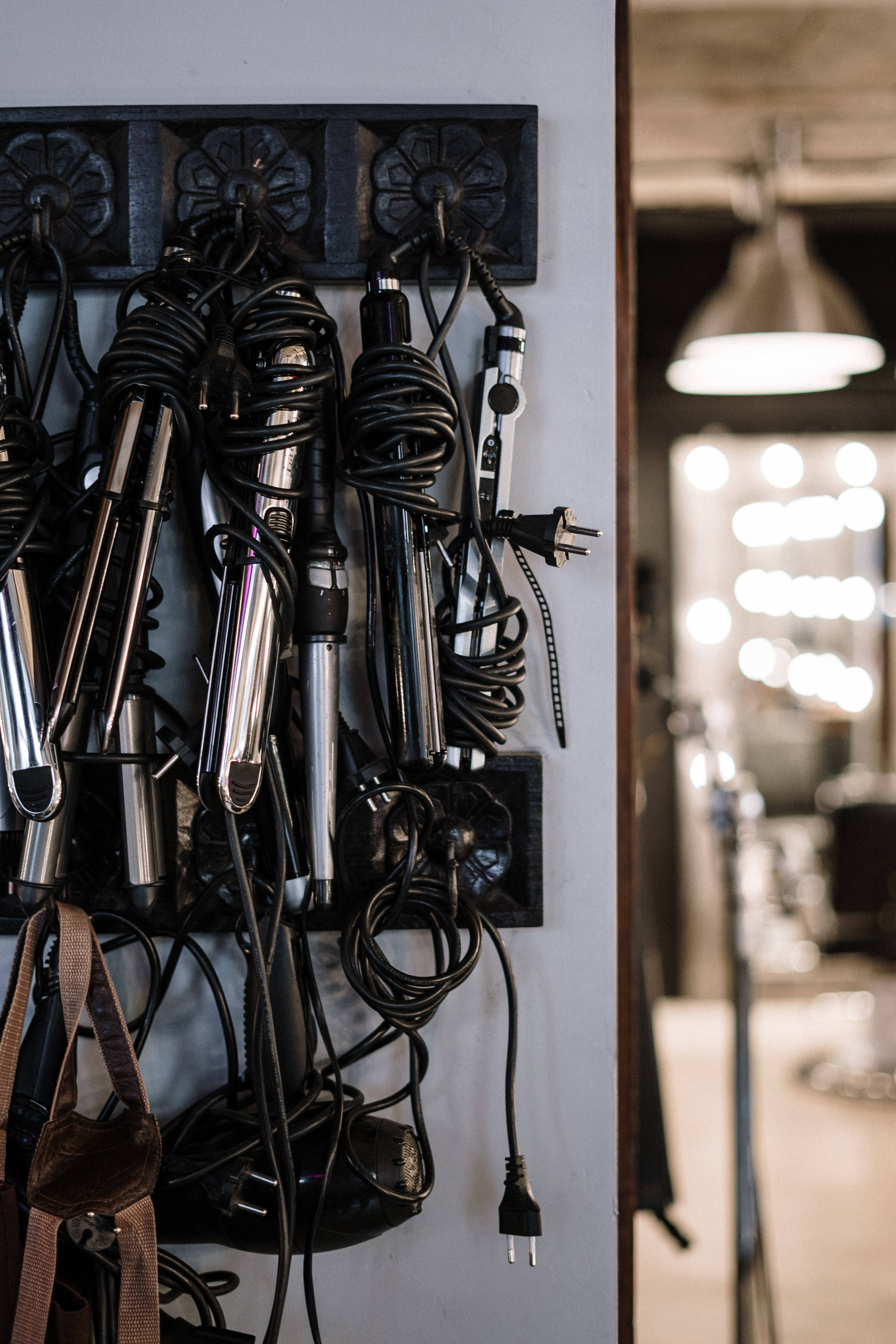 chrome hair tools, tangled black cords, wall-mounted rack, 5K Phone Wallpaper