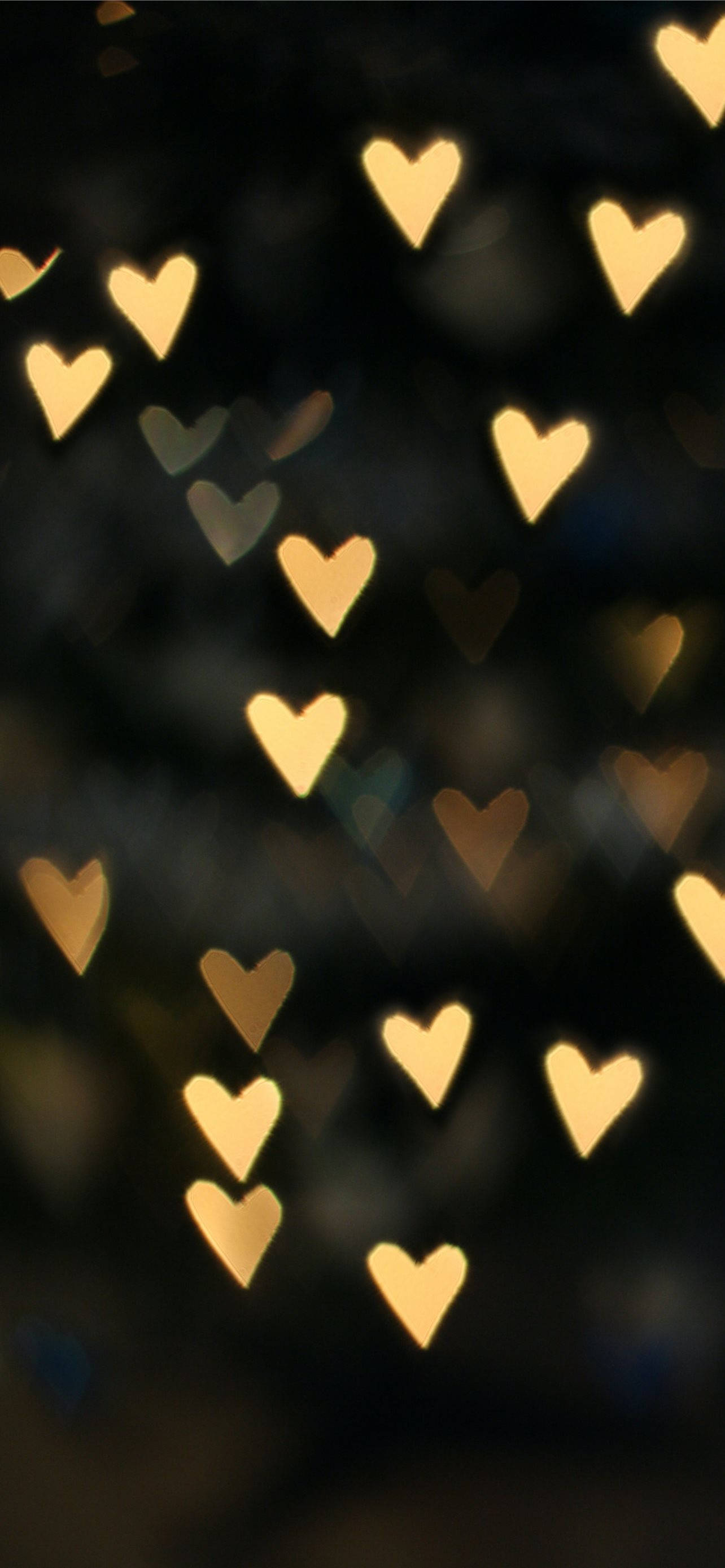 Beige iPhone, golden heart-shaped bokeh lights, dark blurred background, 2K Phone Wallpaper