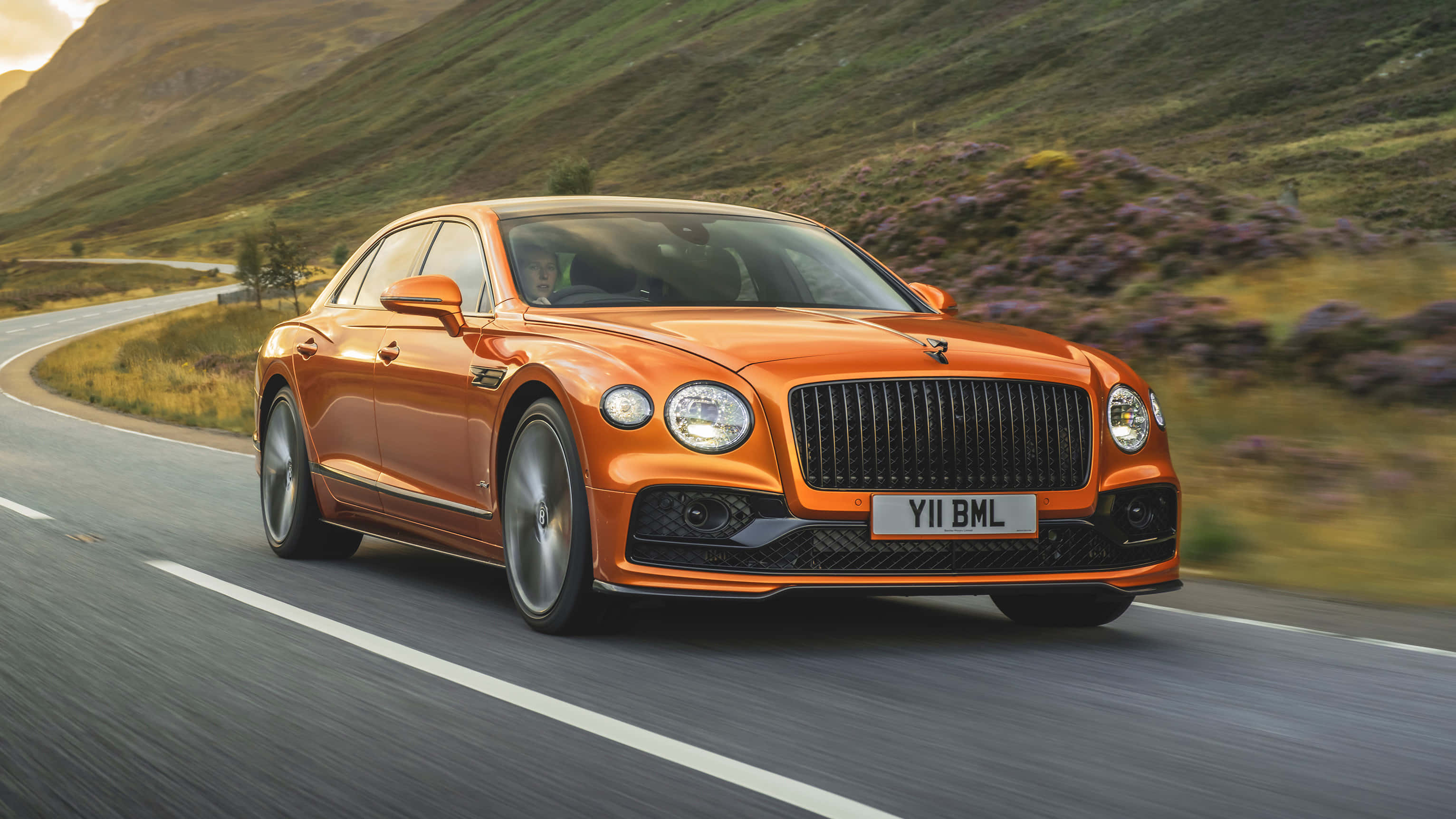 Bentley Flying Spur, vibrant orange, winding mountain road, 2K Desktop Wallpaper