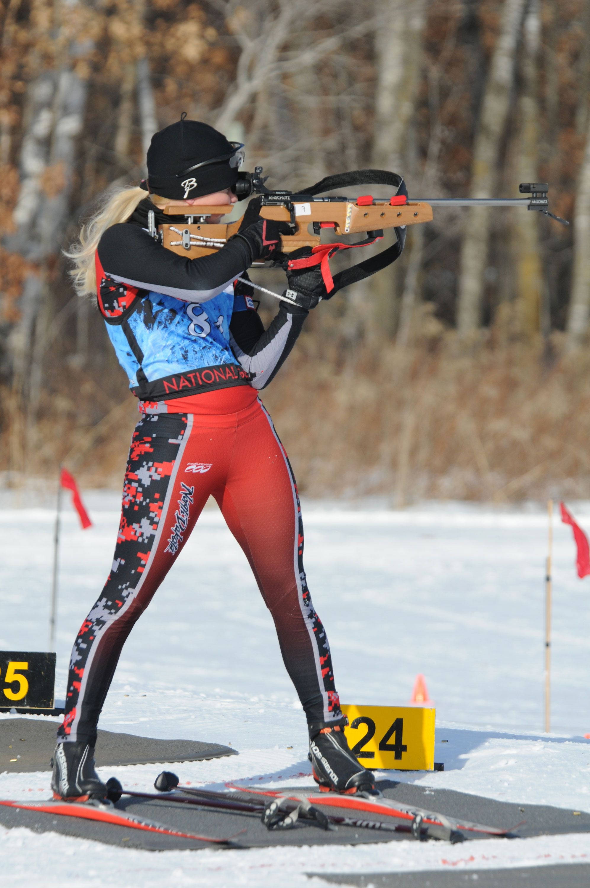 female biathlete, red and black gear, rifle shooting segment, 2K Phone Wallpaper