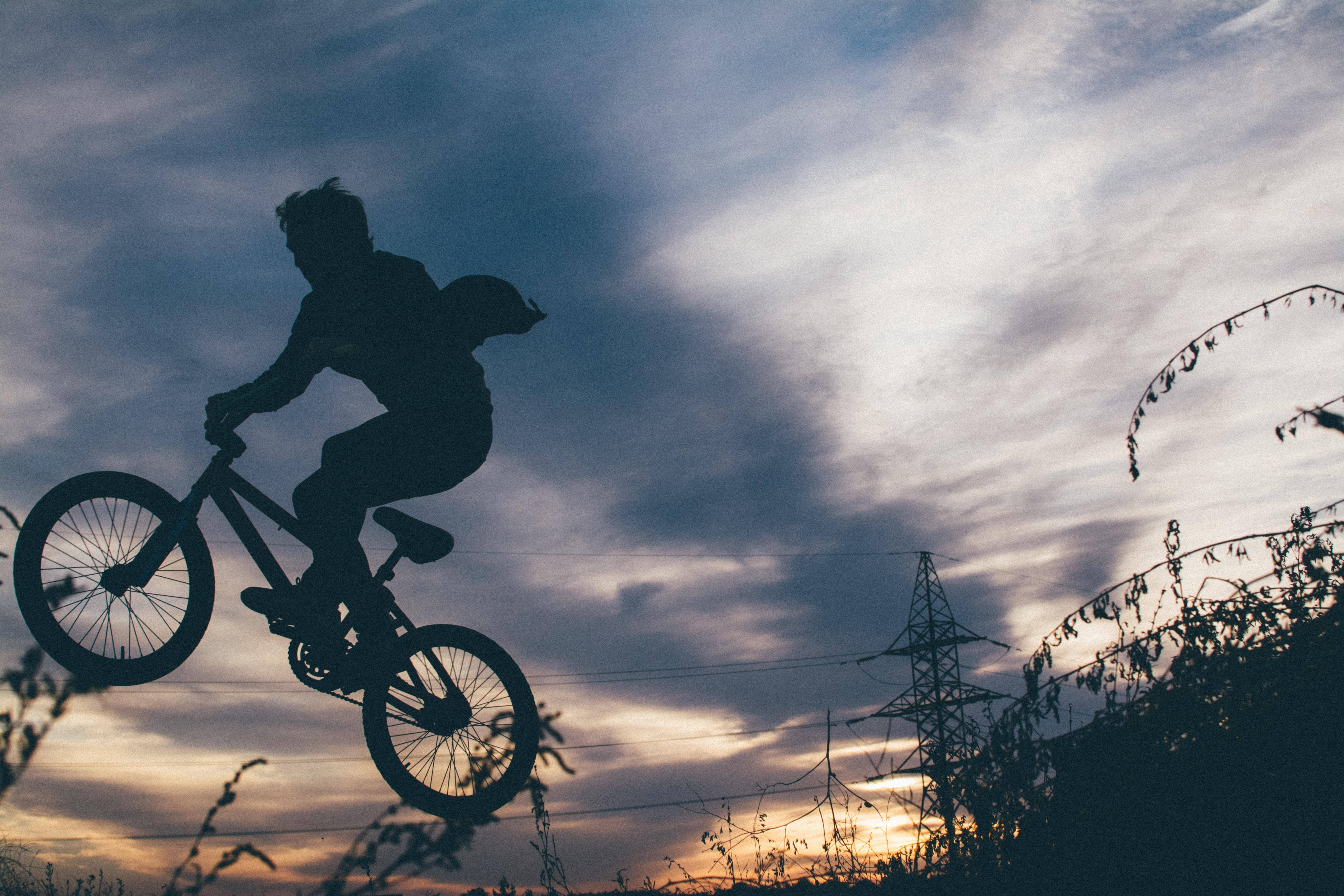 BMX rider, silhouetted mid-air, dramatic sunset sky, 5K Desktop Wallpaper