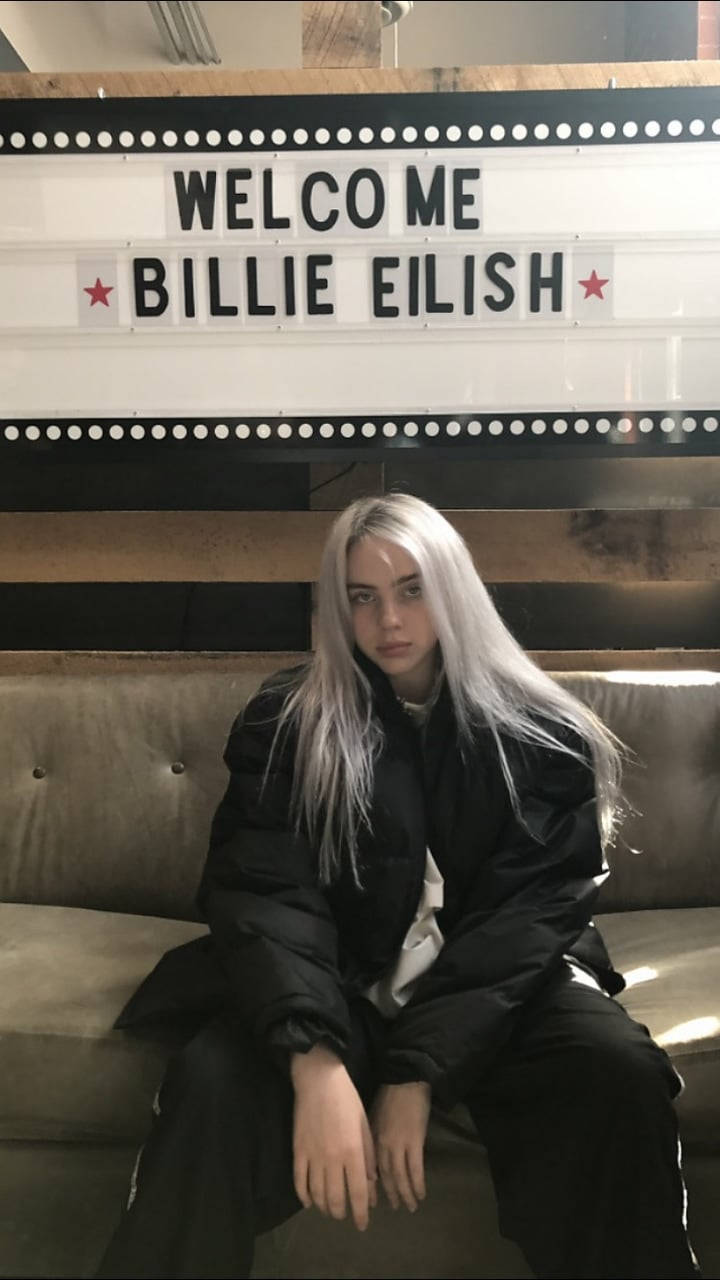 Billie Eilish, beige couch, glowing marquee sign, HD Phone Wallpaper