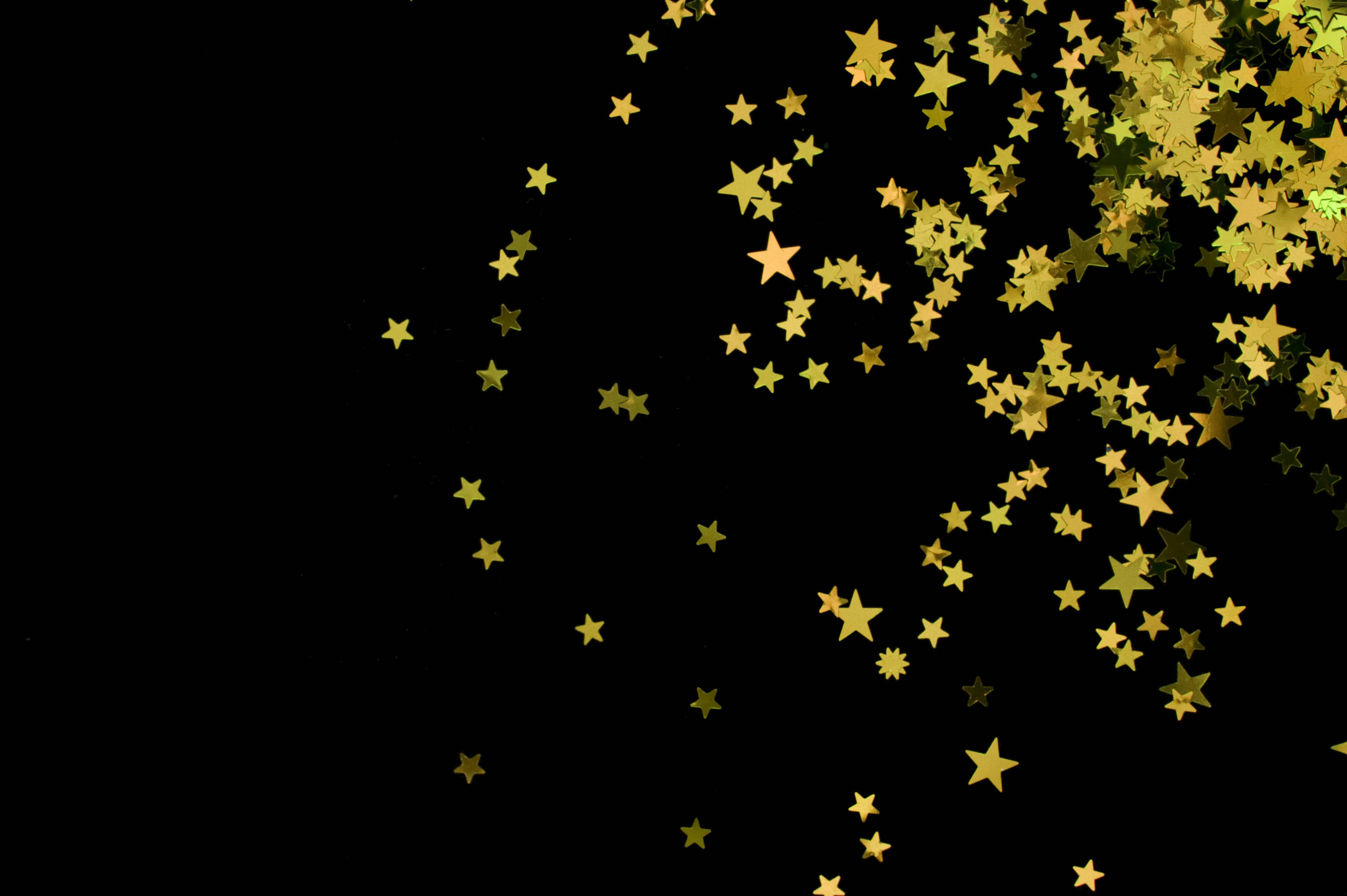 black background, golden star-shaped confetti, festive sparkling effect, 2K Desktop Wallpaper