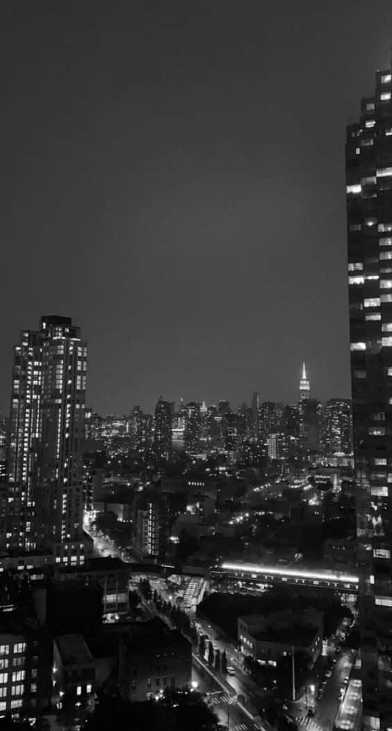 monochrome nighttime cityscape, towering skyscrapers, glowing windows, SD Phone Wallpaper