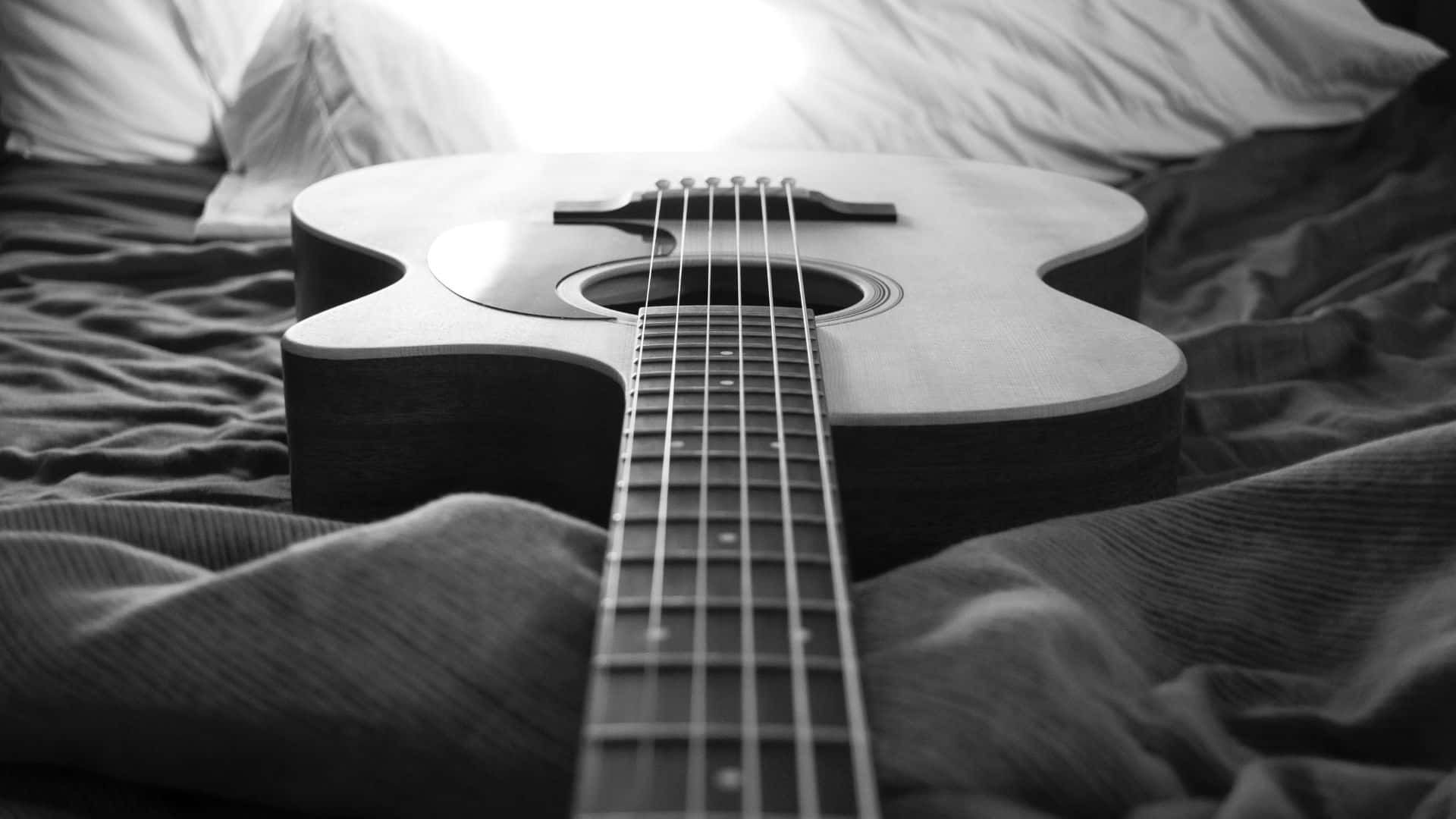 black and white acoustic guitar, rumpled bed sheets, soft light, Full HD Desktop Wallpaper