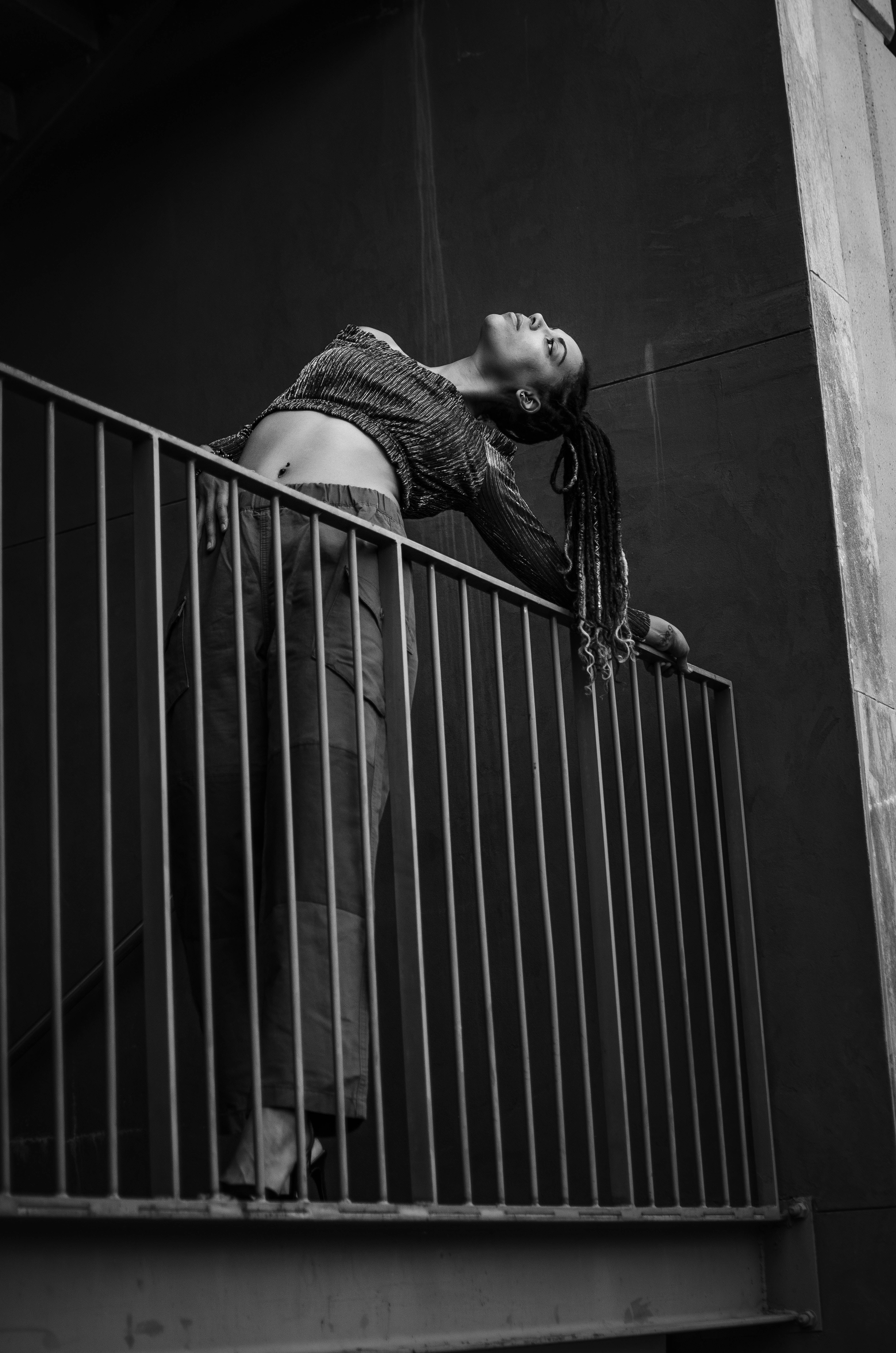 woman with braids, metal railing, dark urban balcony, 8K Phone Wallpaper