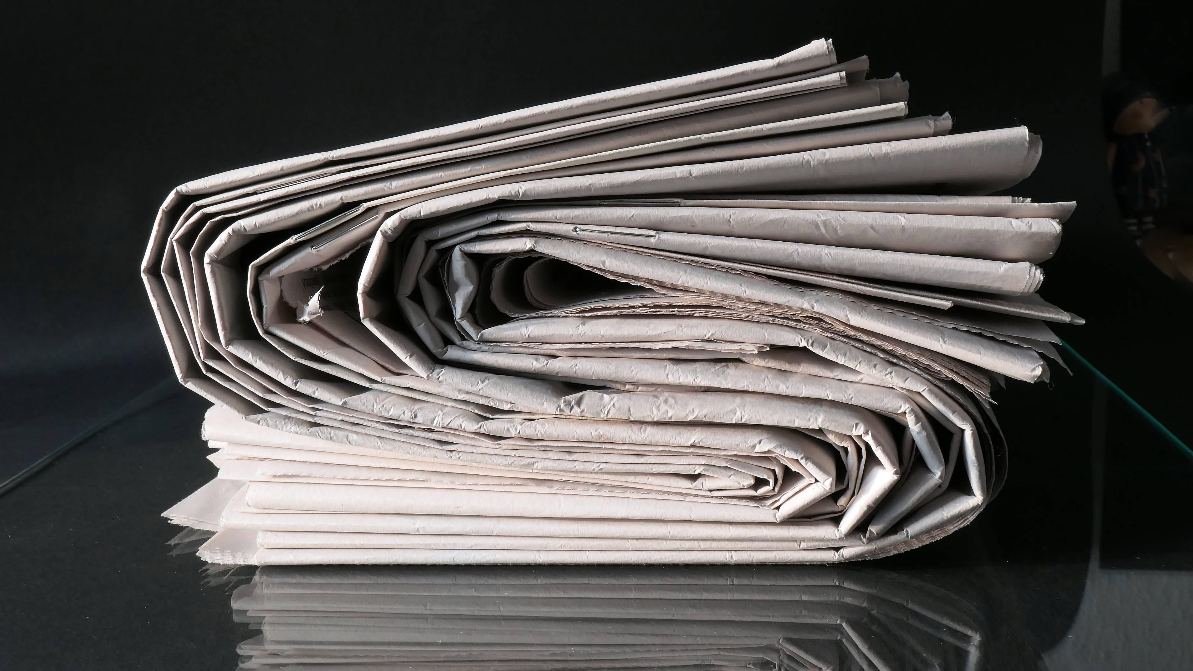 newspaper pile, glossy black surface, sharp reflections, 4K Desktop Wallpaper
