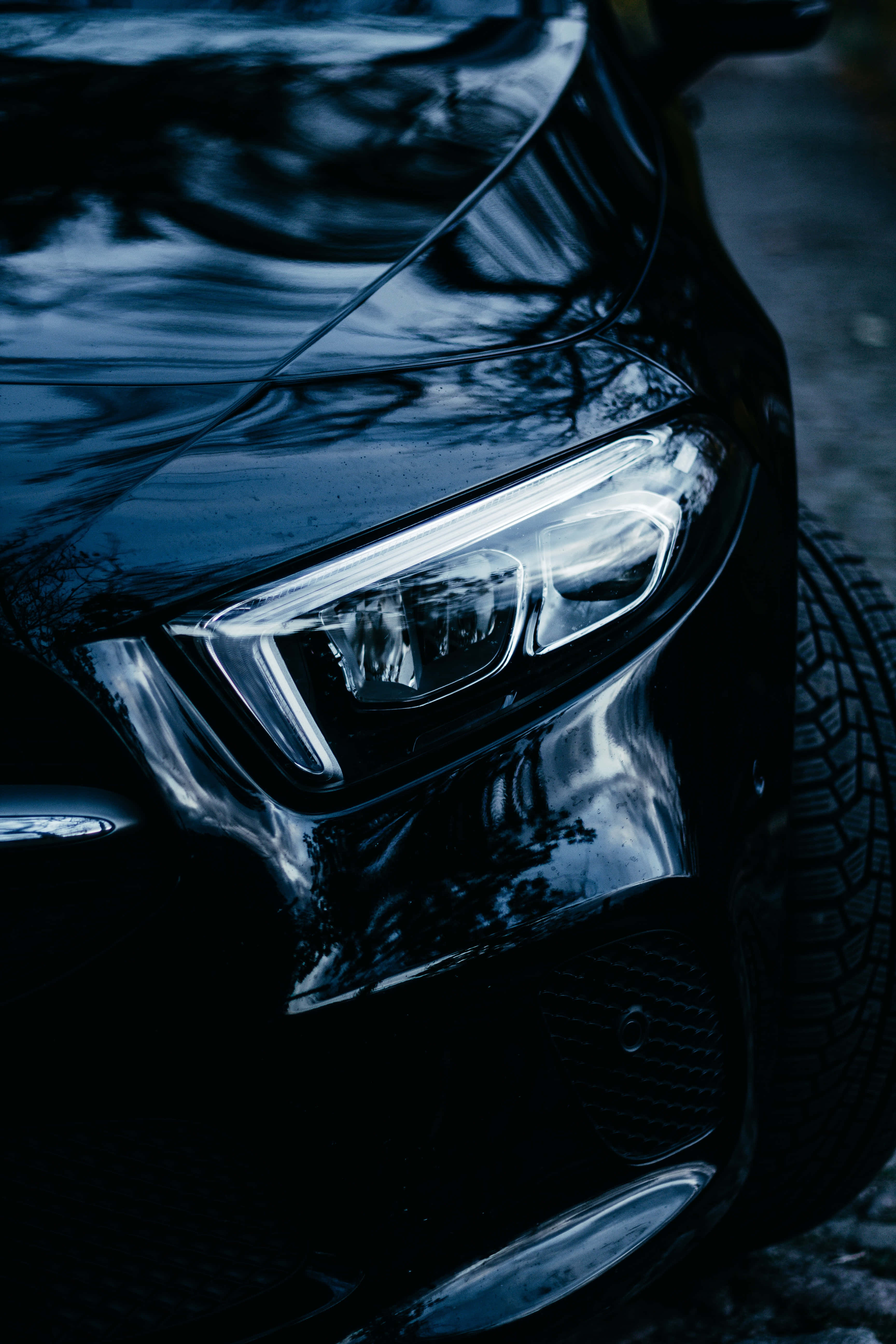 glossy black car, glowing headlight, moody blue tones, 5K Phone Wallpaper