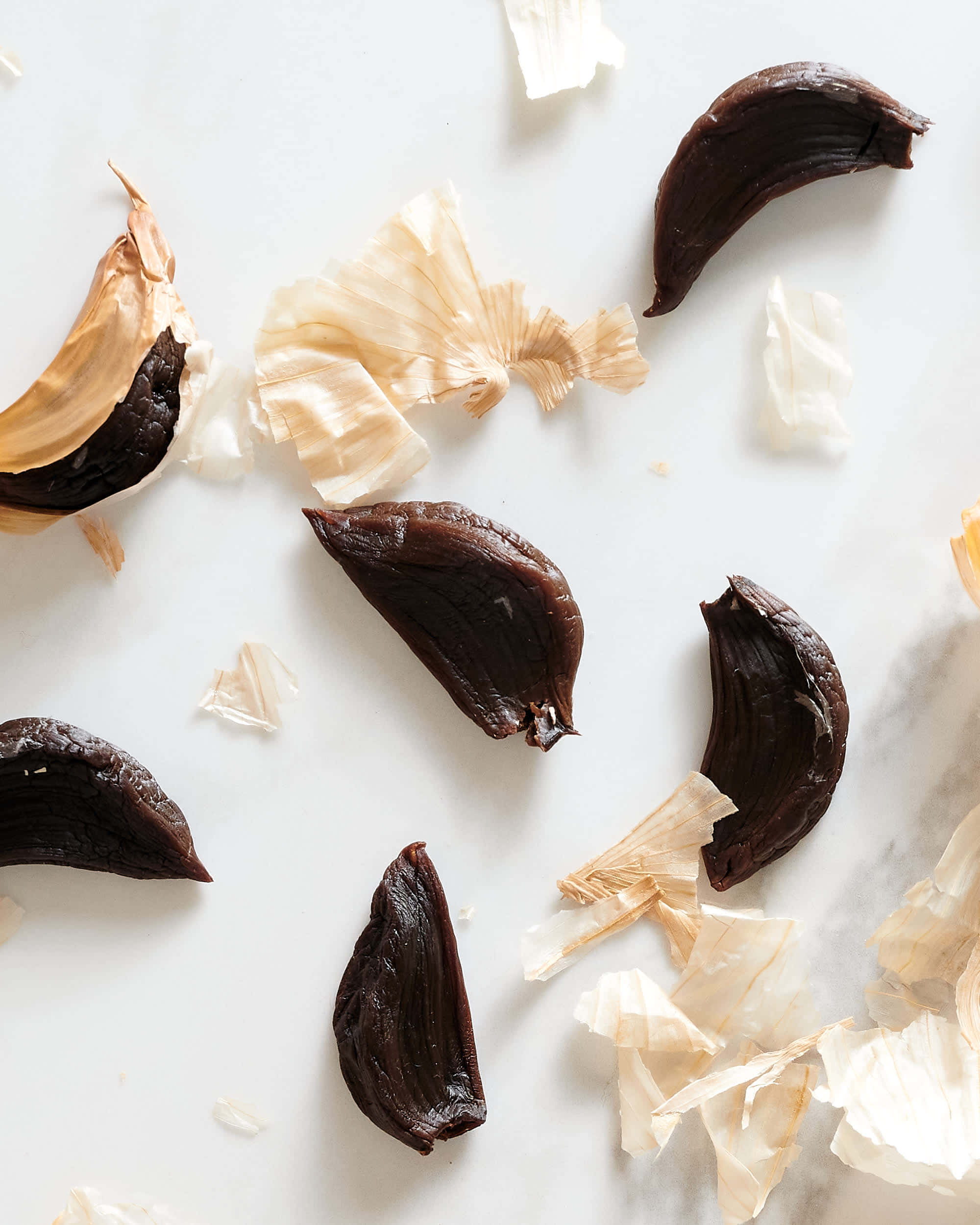 black garlic, white marble surface, dark roasted garlic cloves, Full HD Phone Wallpaper
