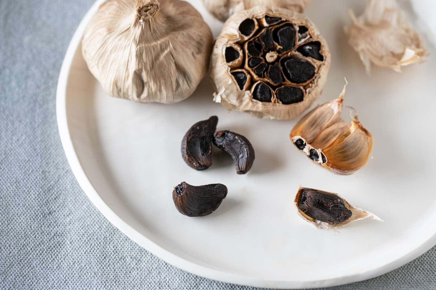 black garlic, white plate, whole garlic bulbs, HD Desktop Wallpaper