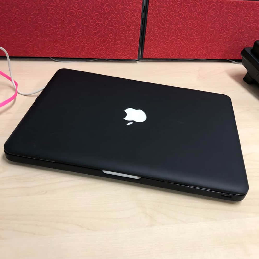 black Macbook, light wood desk, red patterned panels, SD Desktop Wallpaper