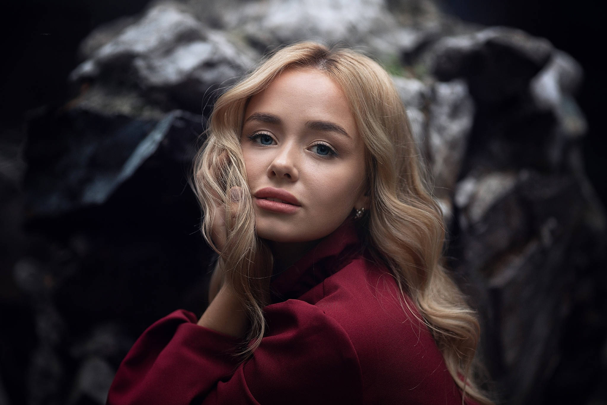 blonde female model, red coat, dark rocky backdrop, Full HD Desktop Wallpaper
