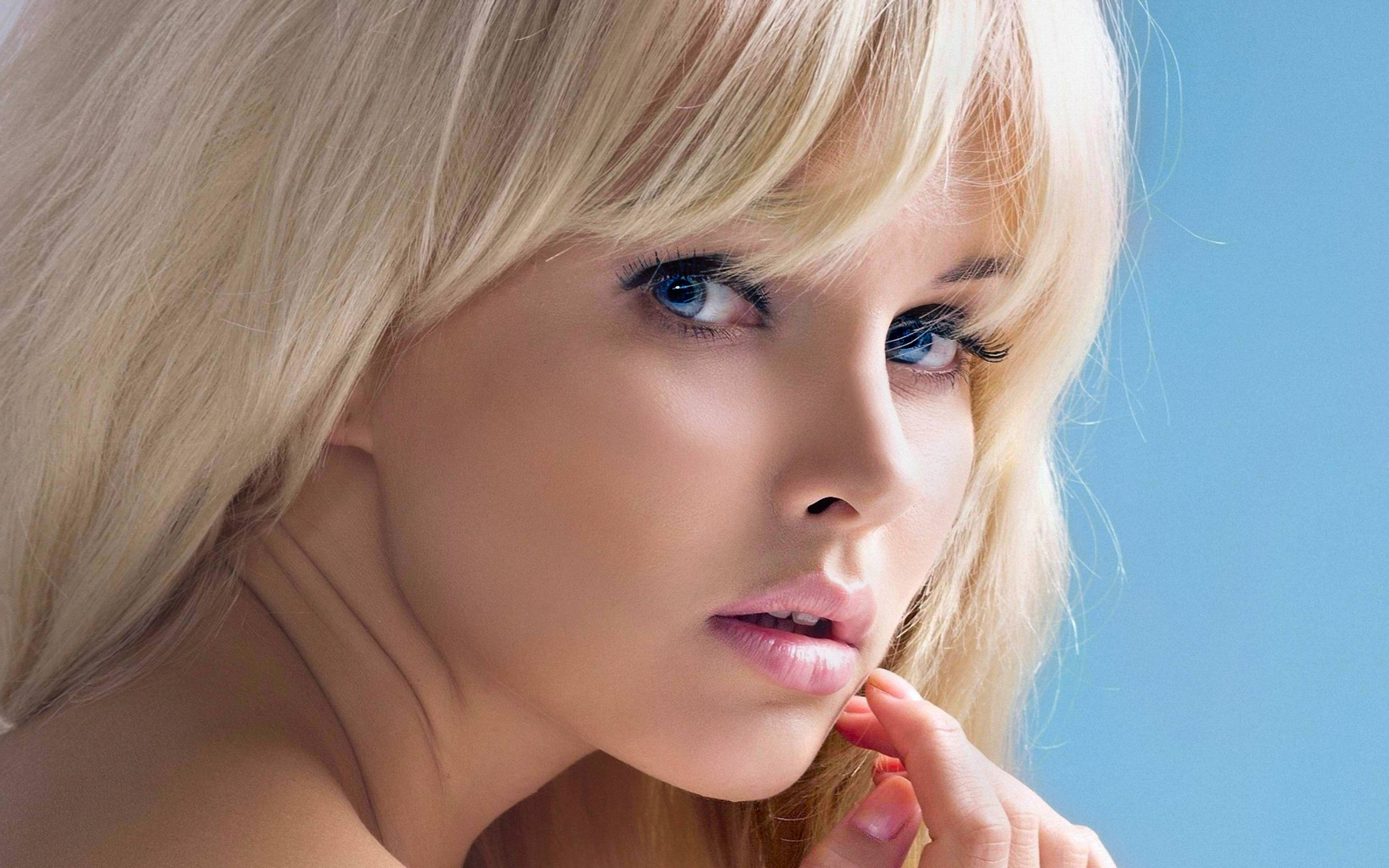 blonde woman, piercing blue eyes, solid blue background, 4K Desktop Wallpaper
