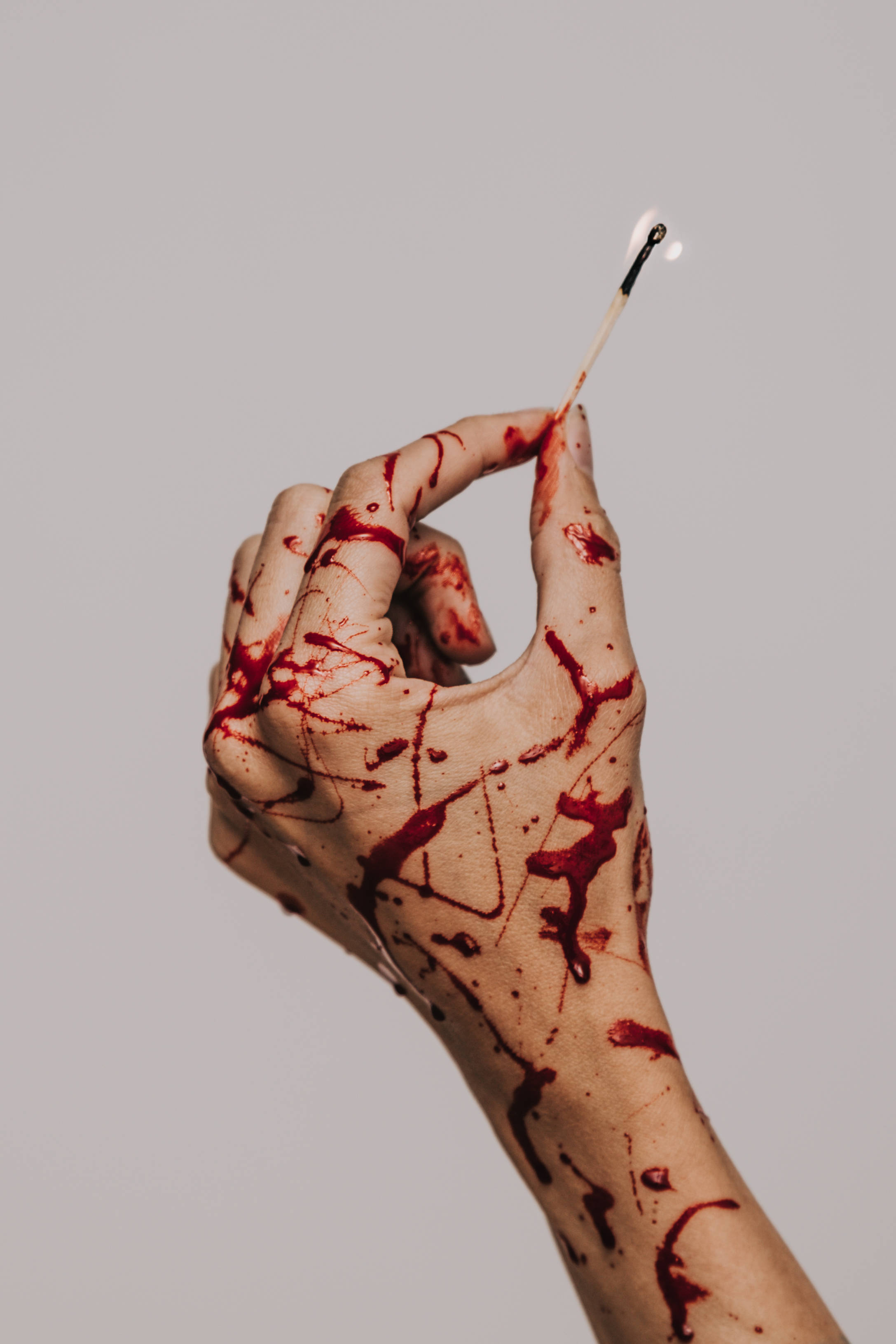 red blood, lit match, plain gray background, 2K Phone Wallpaper