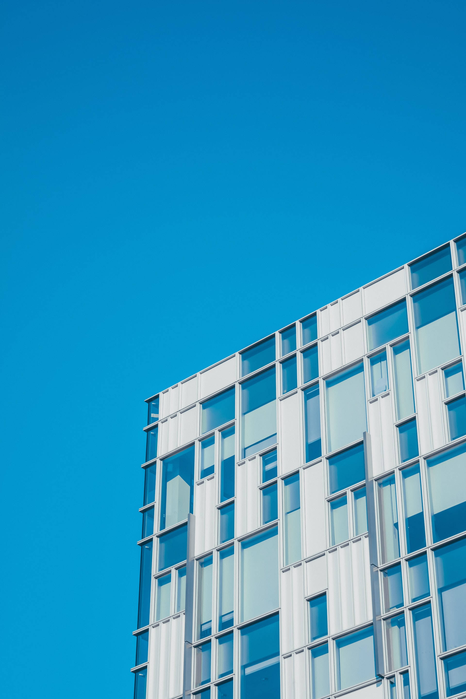 blue checkered building, glass and steel building, vibrant clear blue sky, 2K Phone Wallpaper