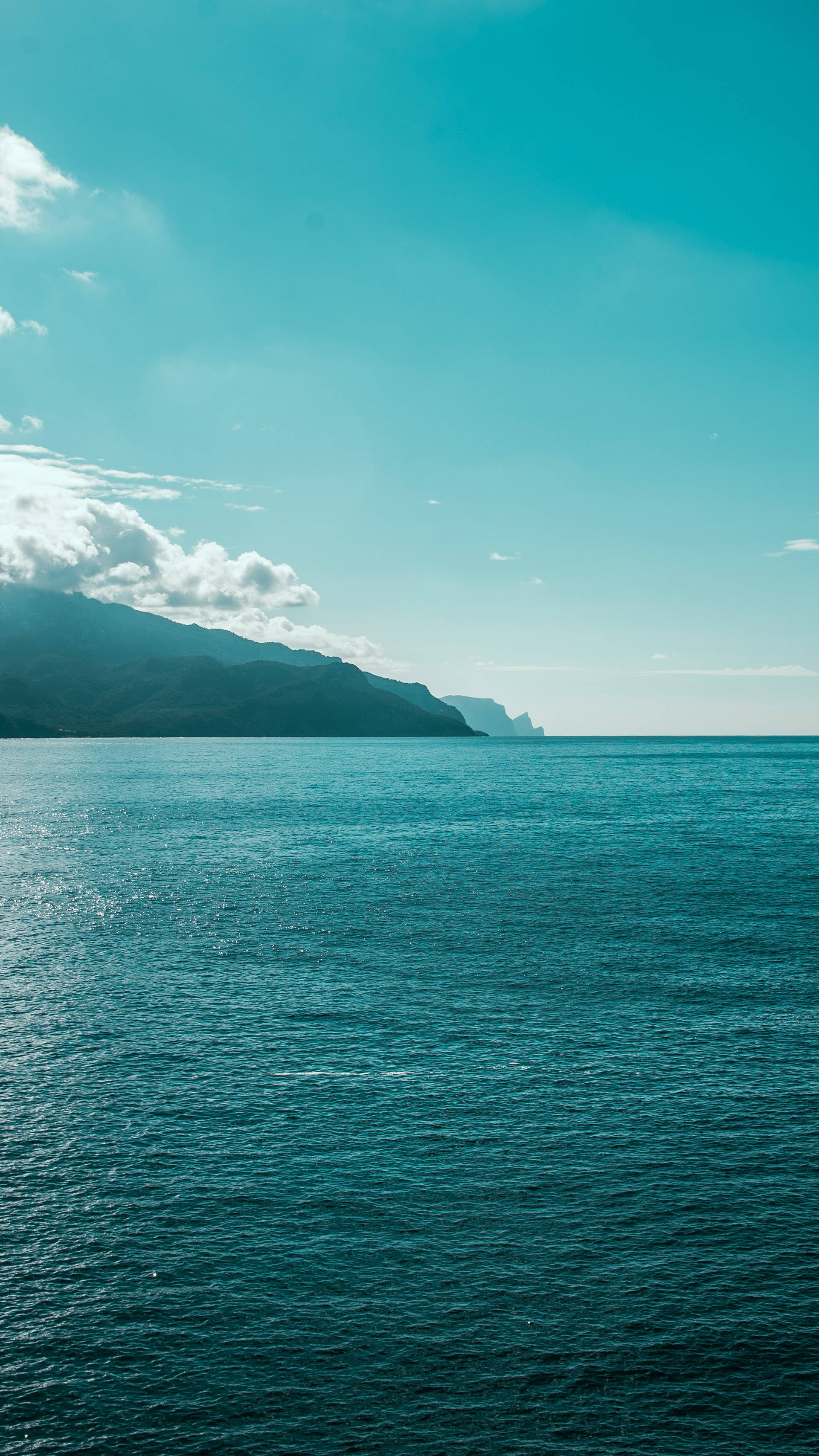 turquoise ocean, distant mountainous coastline, bright clear sky, 2K Phone Wallpaper