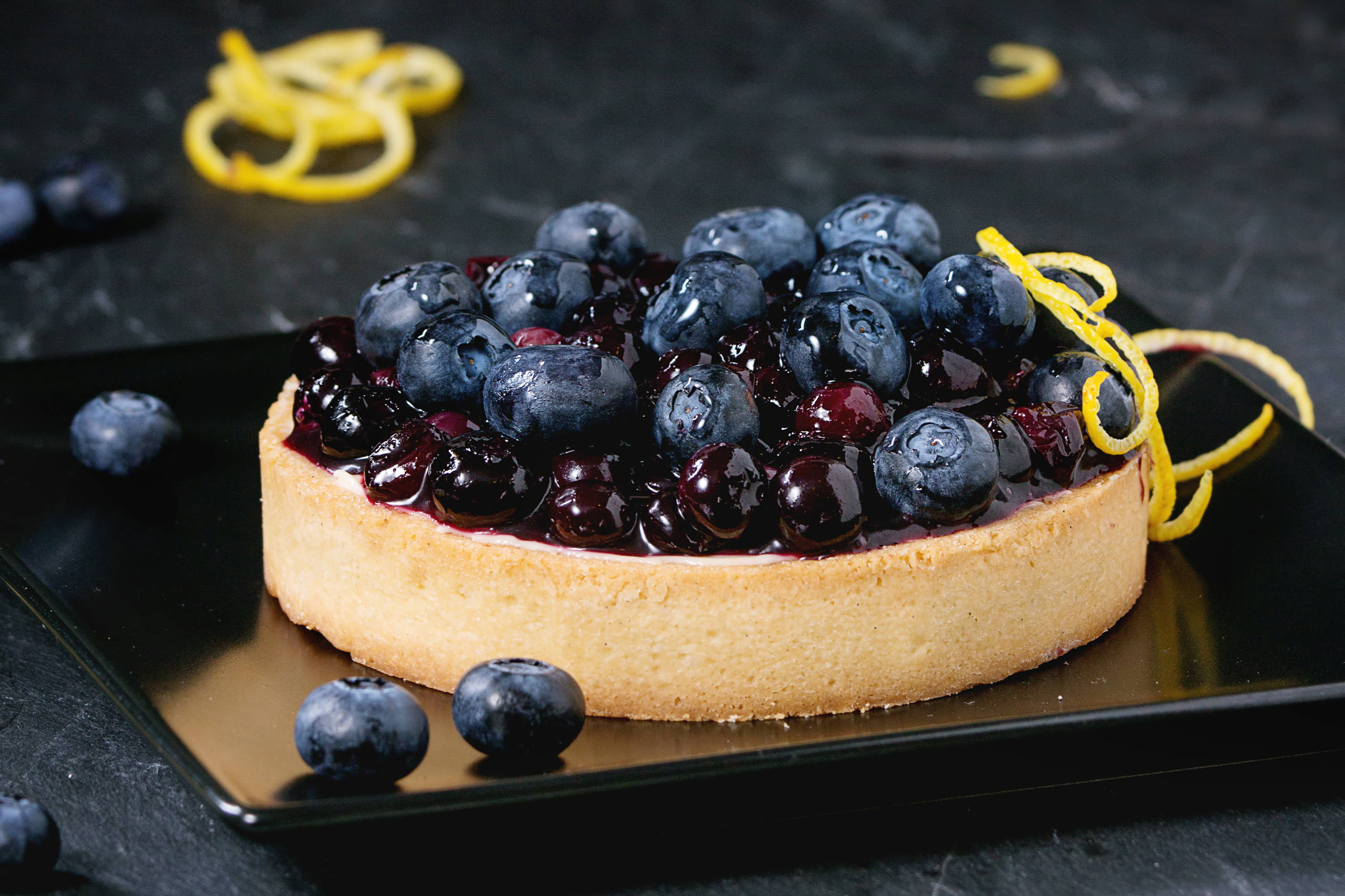 blueberry tart, lemon zest garnish, black plate, 2K Desktop Wallpaper