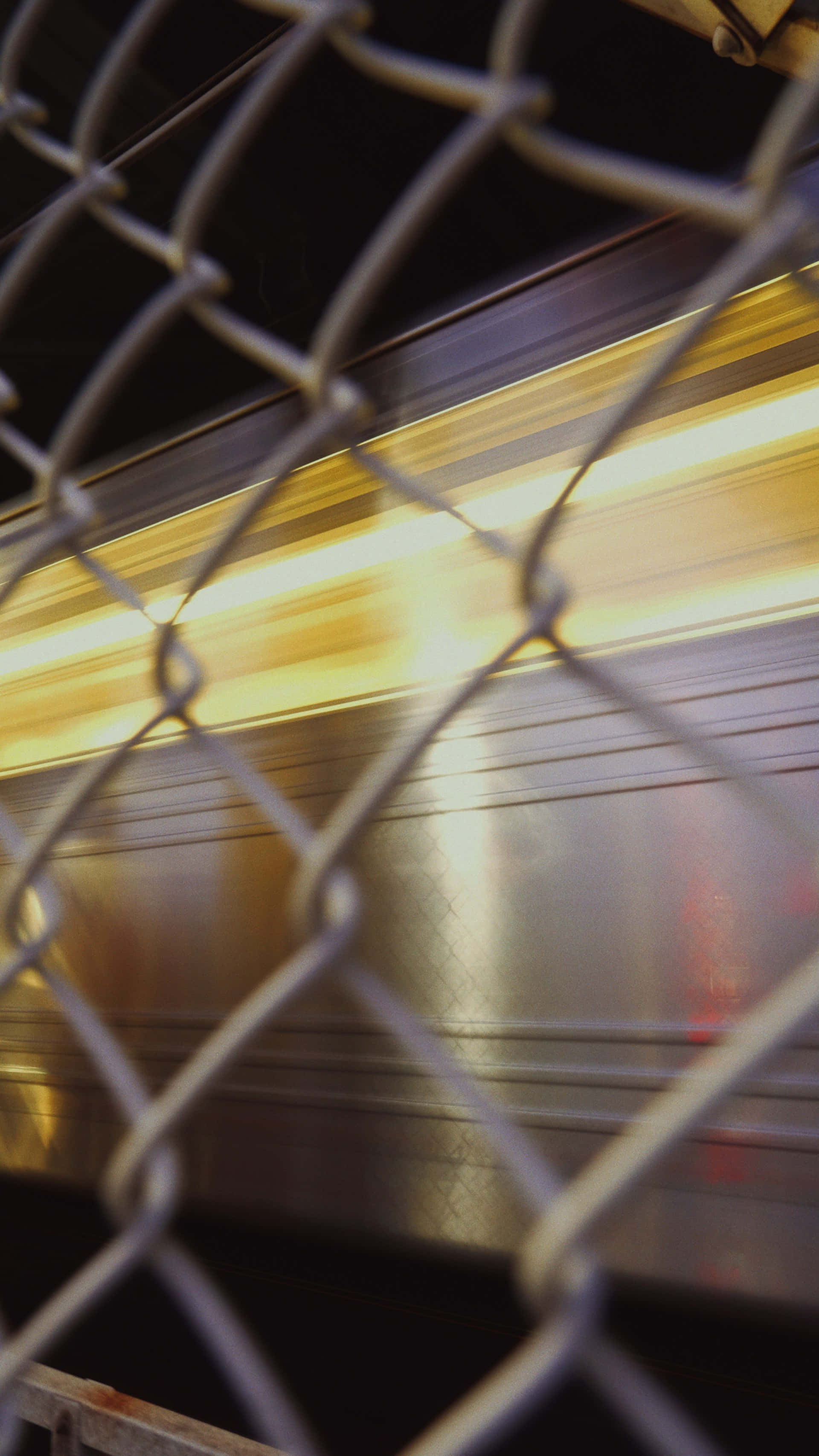 speeding train, golden lights, chain link fence, 2K Phone Wallpaper