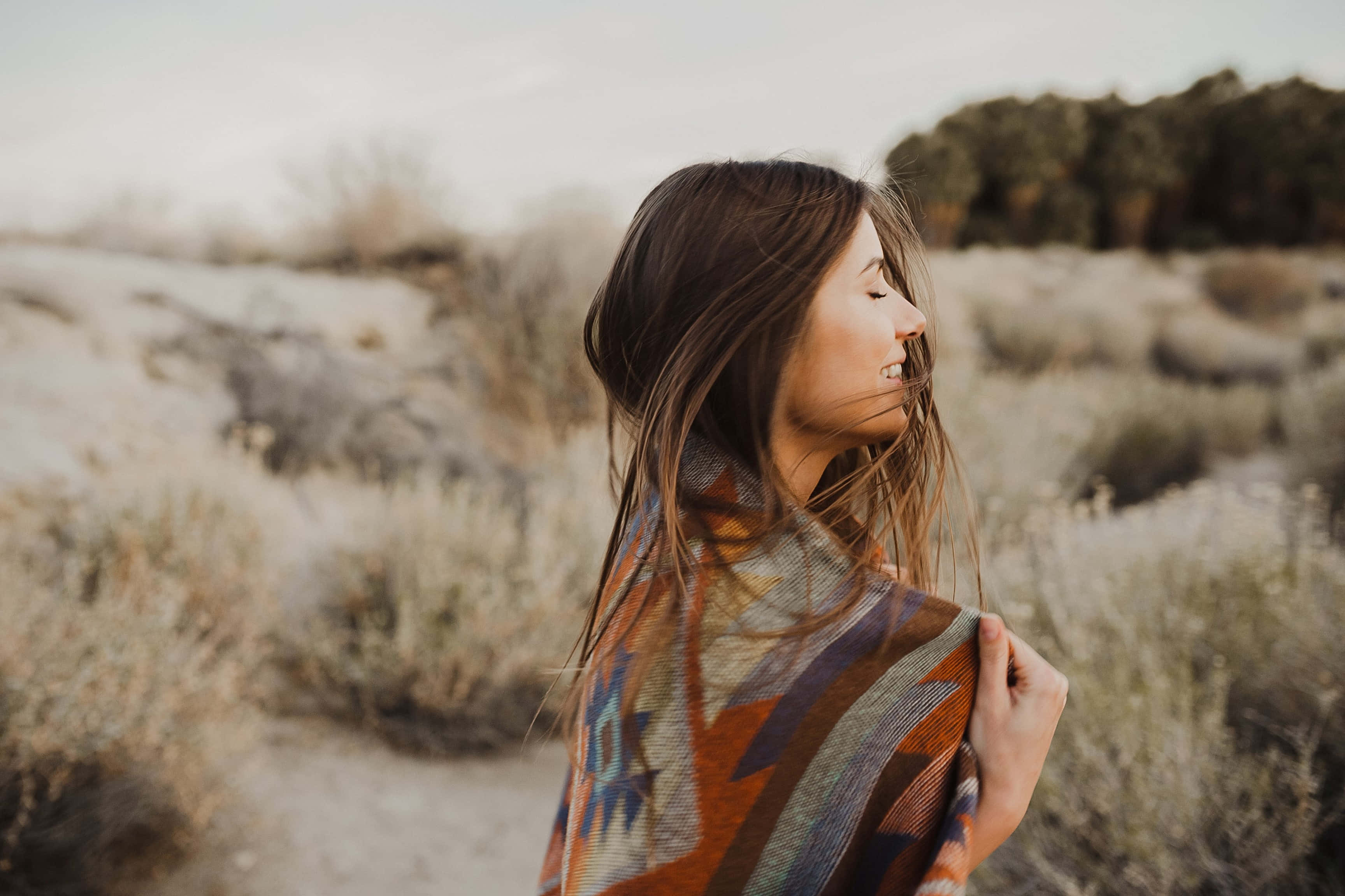 boho hippie style woman, colorful patterned blanket, dry grassy field, 2K Desktop Wallpaper