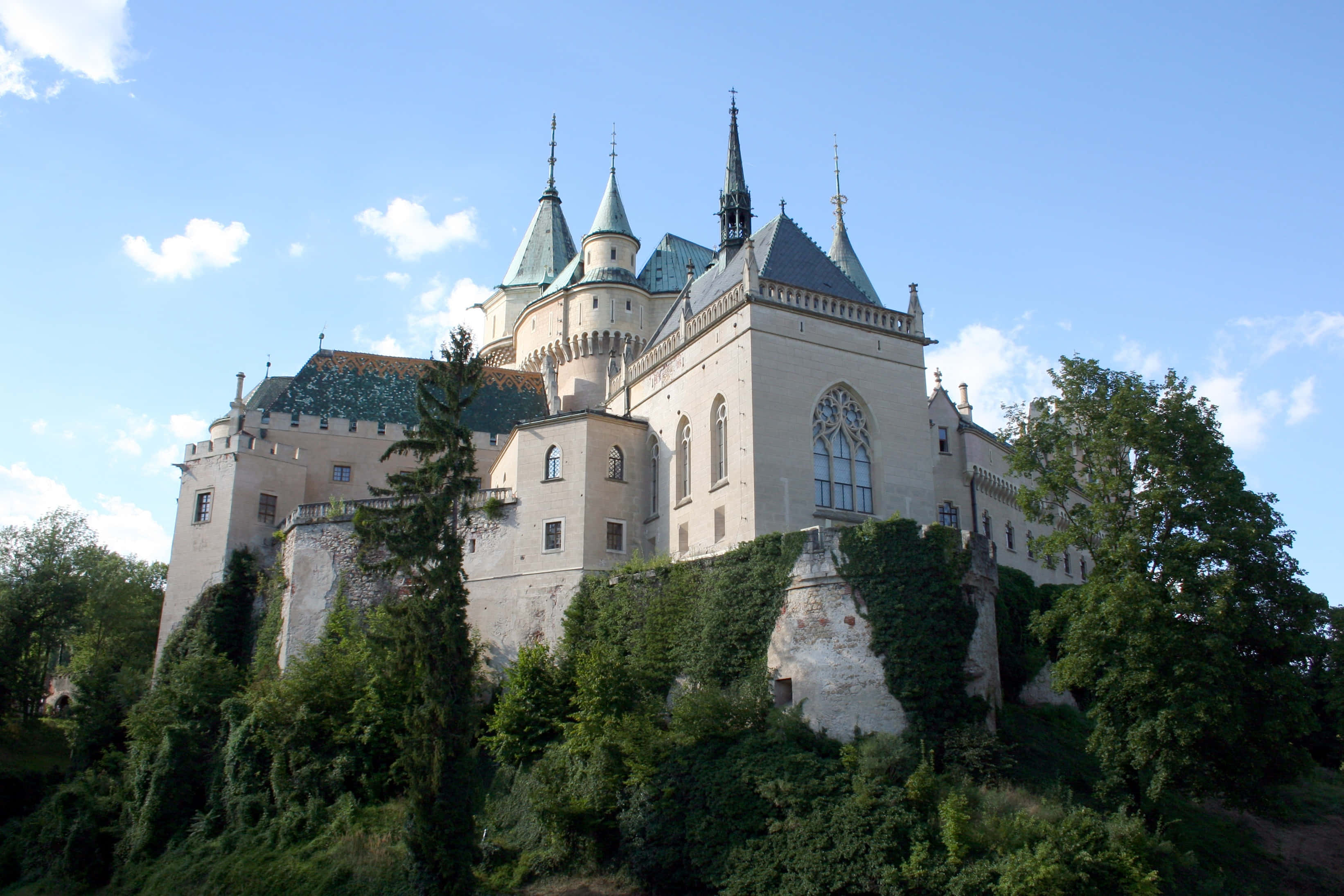 Bojnice Castle, green-tiled spires, lush hill, 2K Desktop Wallpaper