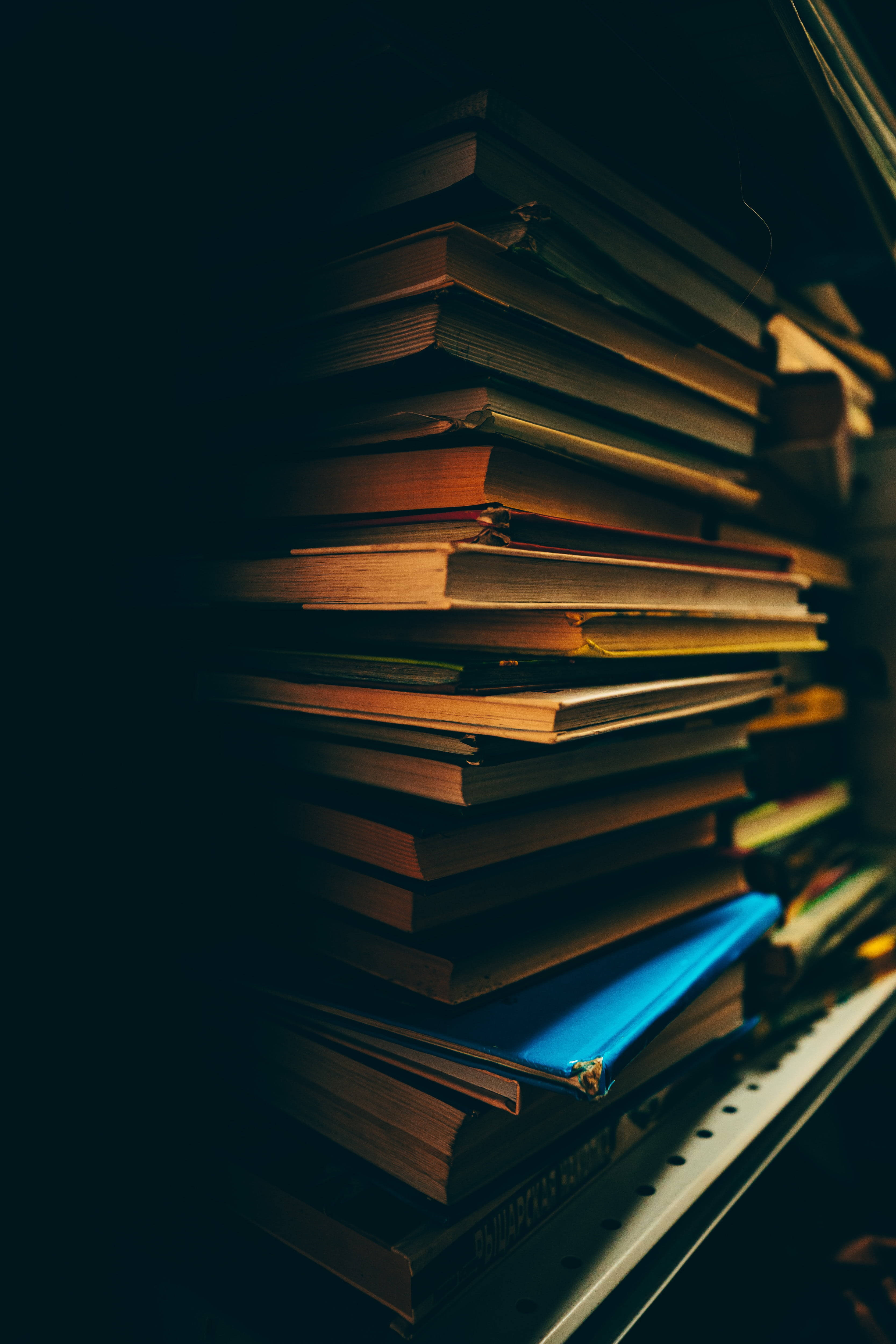 pile of books, warm light, dark background, 4K Phone Wallpaper