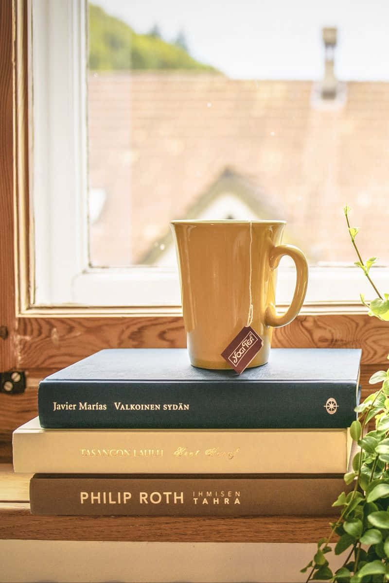 Books iPhone, yellow tea mug, stack of books, SD Phone Wallpaper