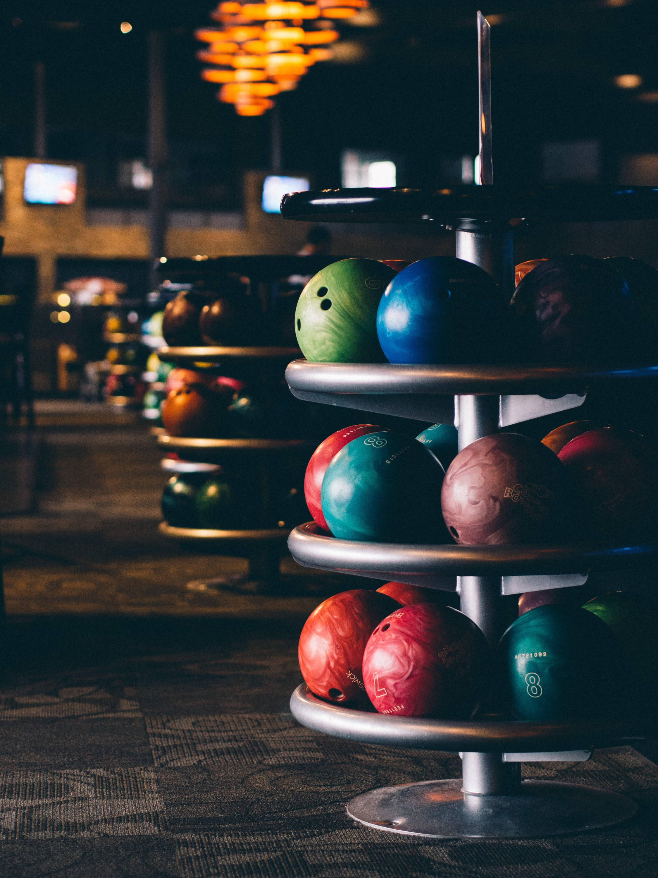 bowling balls, dimly lit alley, warm overhead lights, 2K Phone Wallpaper