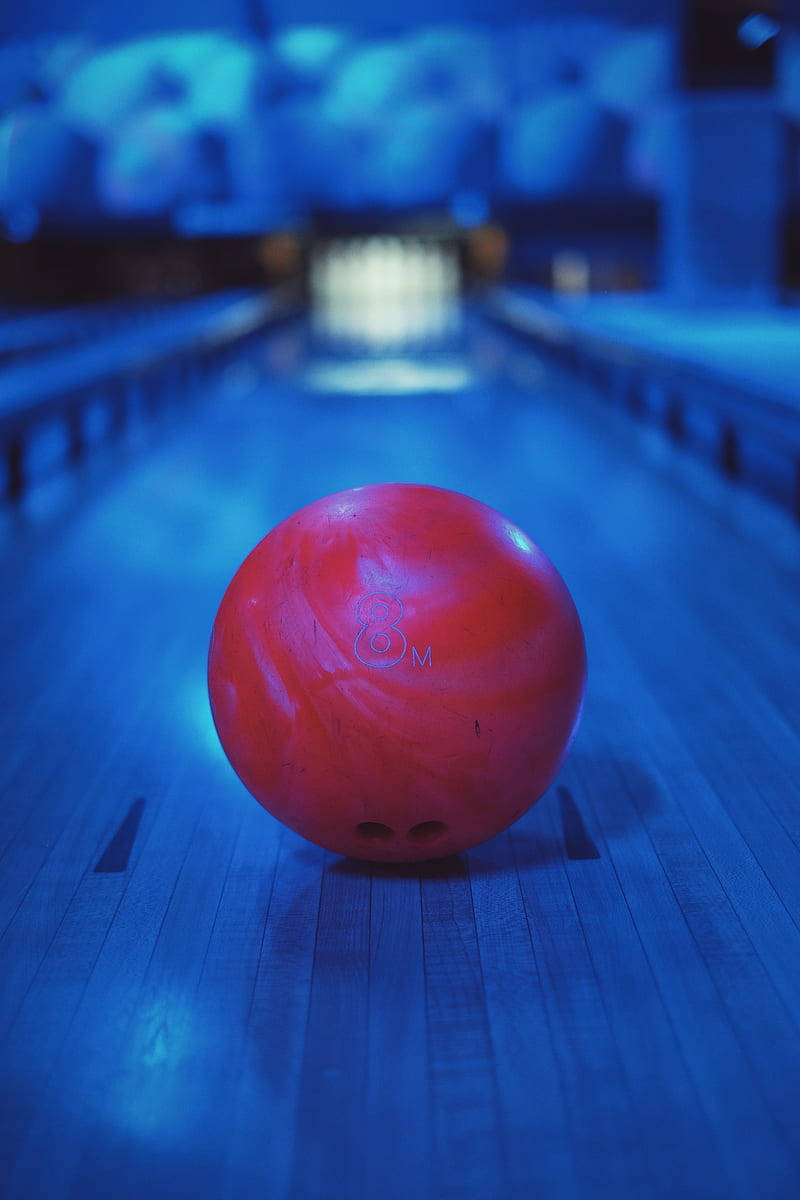 red bowling ball, glossy blue-lit lane, blurred pins, SD Phone Wallpaper