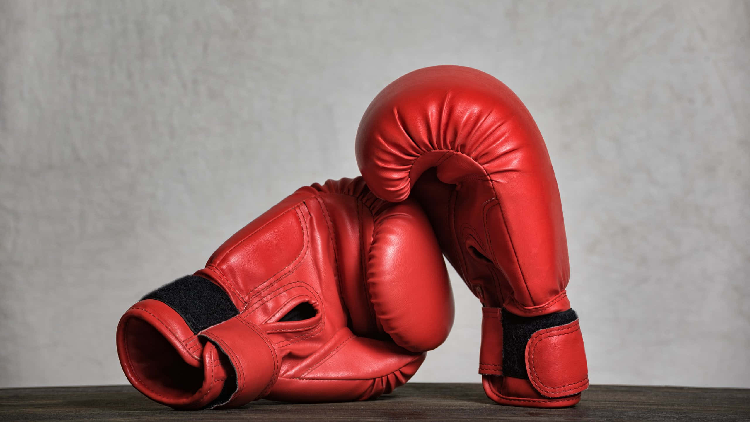 red boxing gloves, black wrist straps, dark wooden surface, 2K Desktop Wallpaper