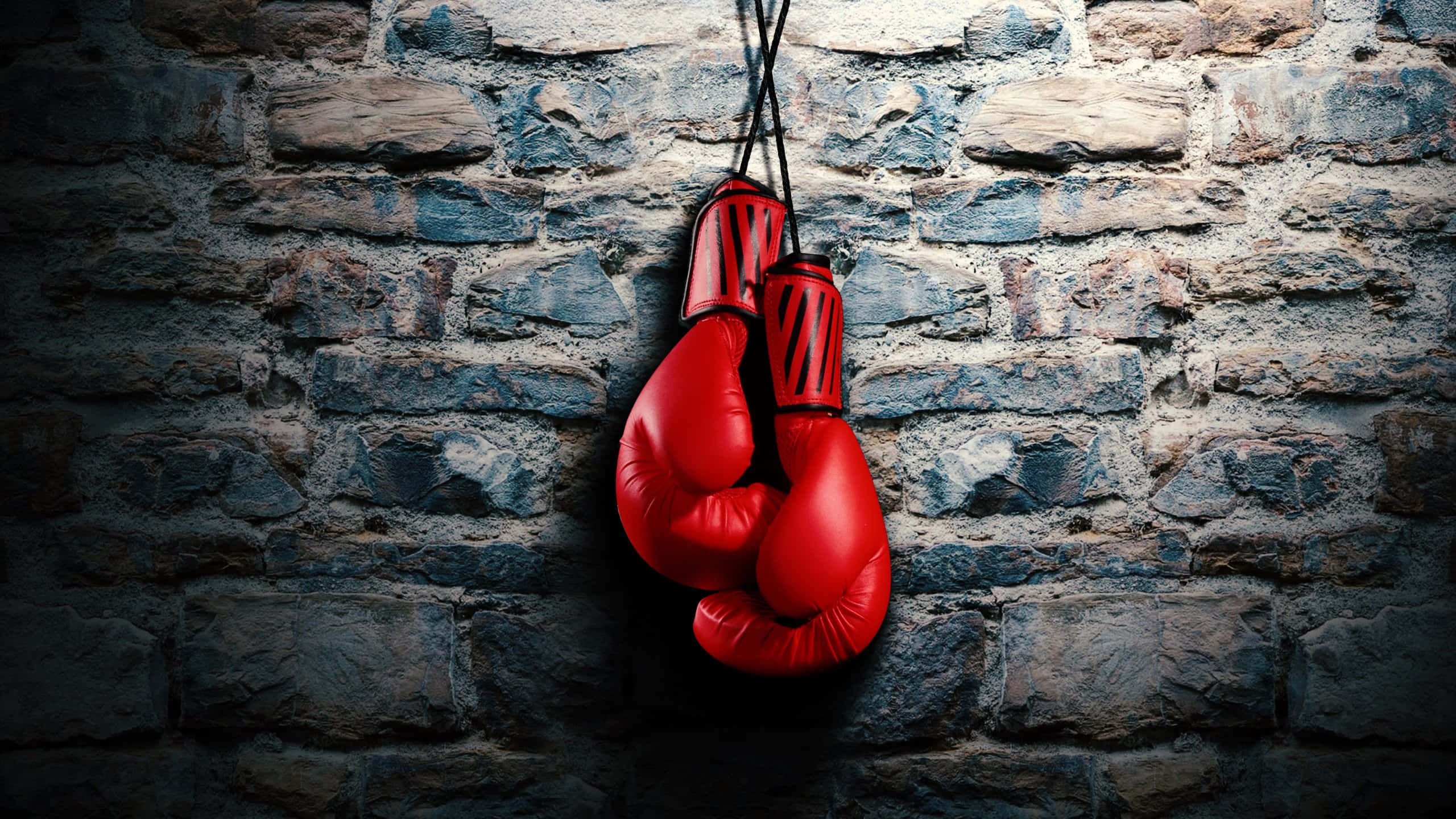 red boxing gloves, black laces, textured gray stone brick wall, 2K Desktop Wallpaper